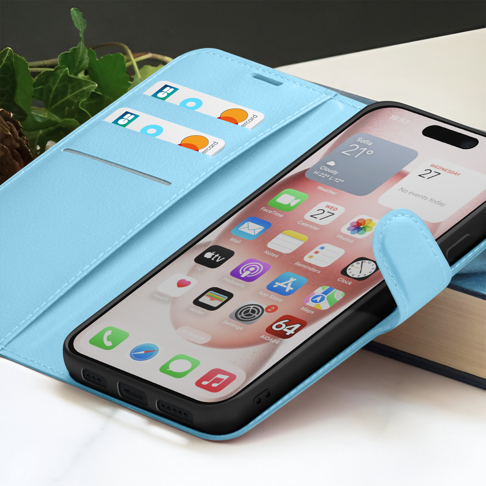 Un smartphone dans un étui bleu clair est posé sur un livre. L'écran affiche des informations météorologiques et des icônes d'applications.