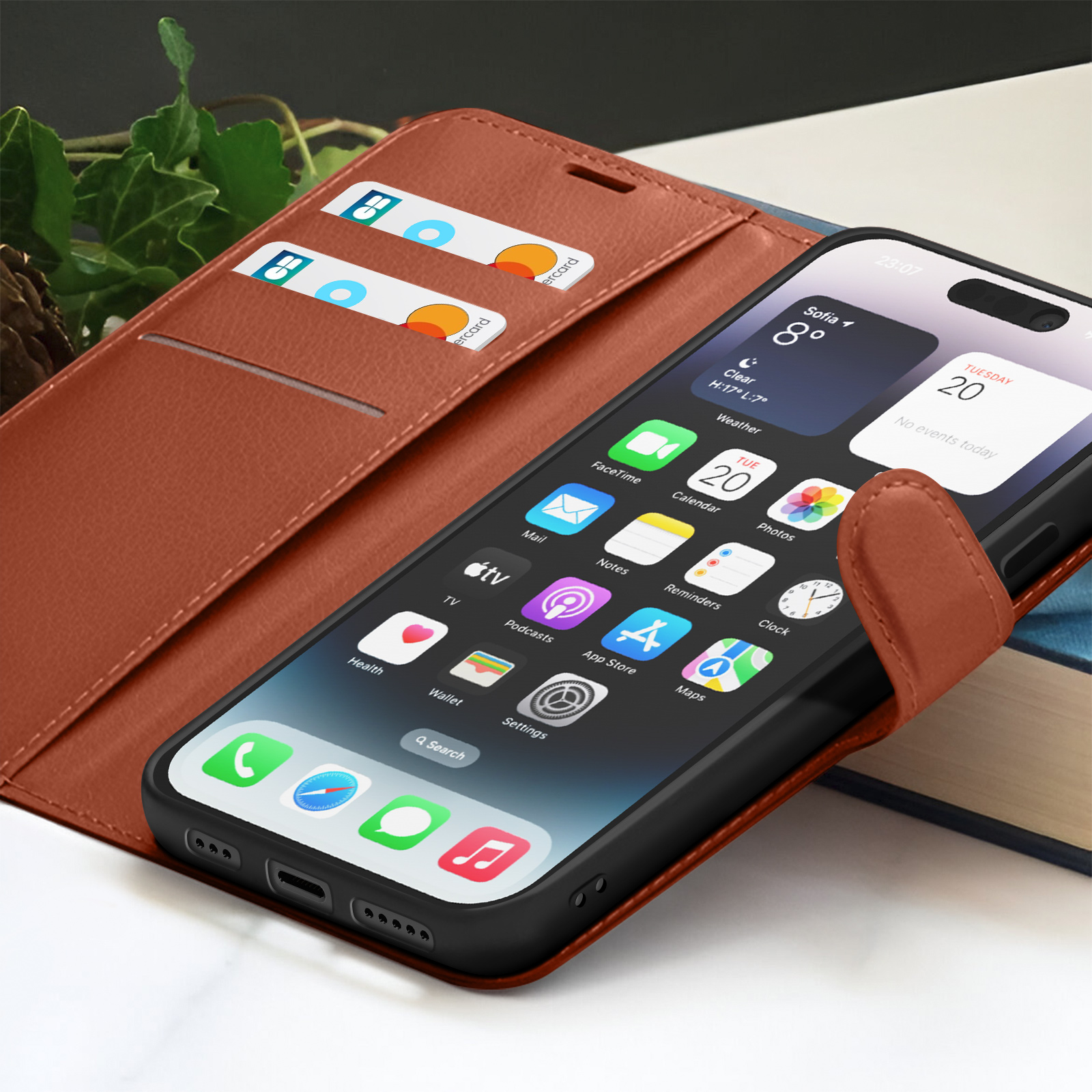 Un iPhone dans un étui en cuir marron affiche son écran d'accueil. Deux cartes de crédit sont visibles dans les fentes de l'étui.