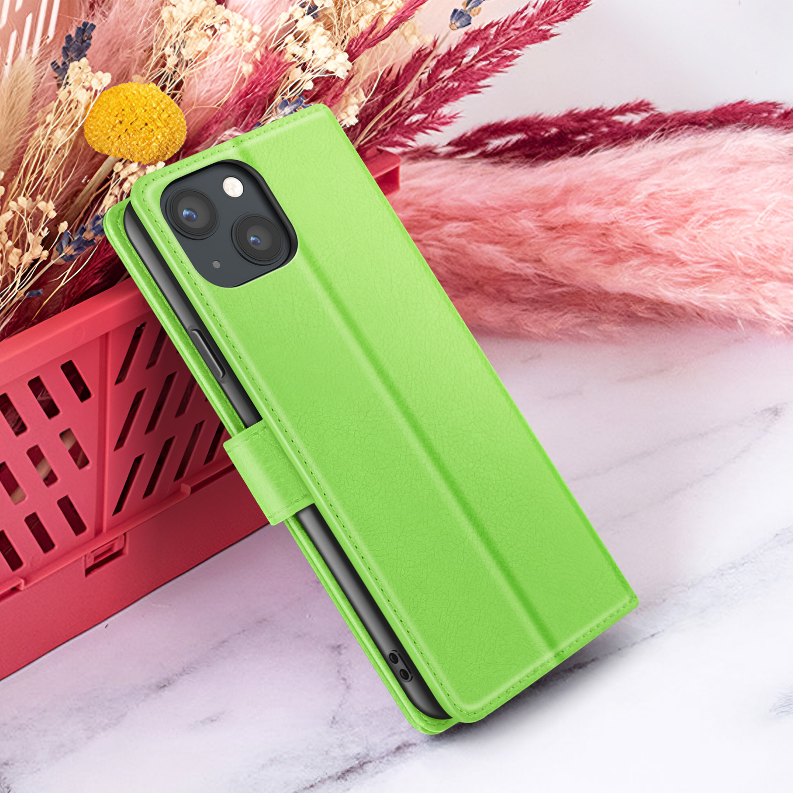Groene telefoonhoes met telefoon erin, geplaatst op een marmeren oppervlak. Droogbloemen op de achtergrond, in een rode mand.