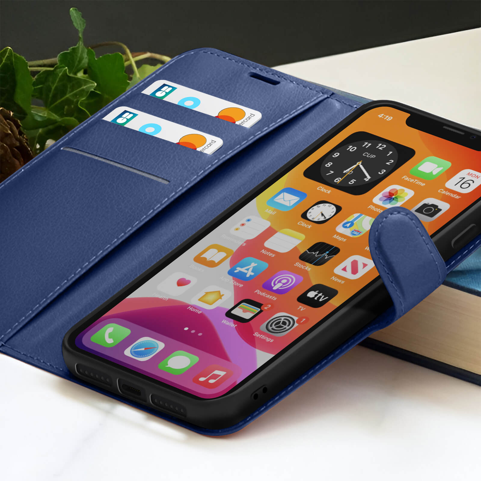 Blauwe telefoonhoes met een smartphone die apps weergeeft. Creditcards in de hoes. Een boek en groene bladeren op de achtergrond.
