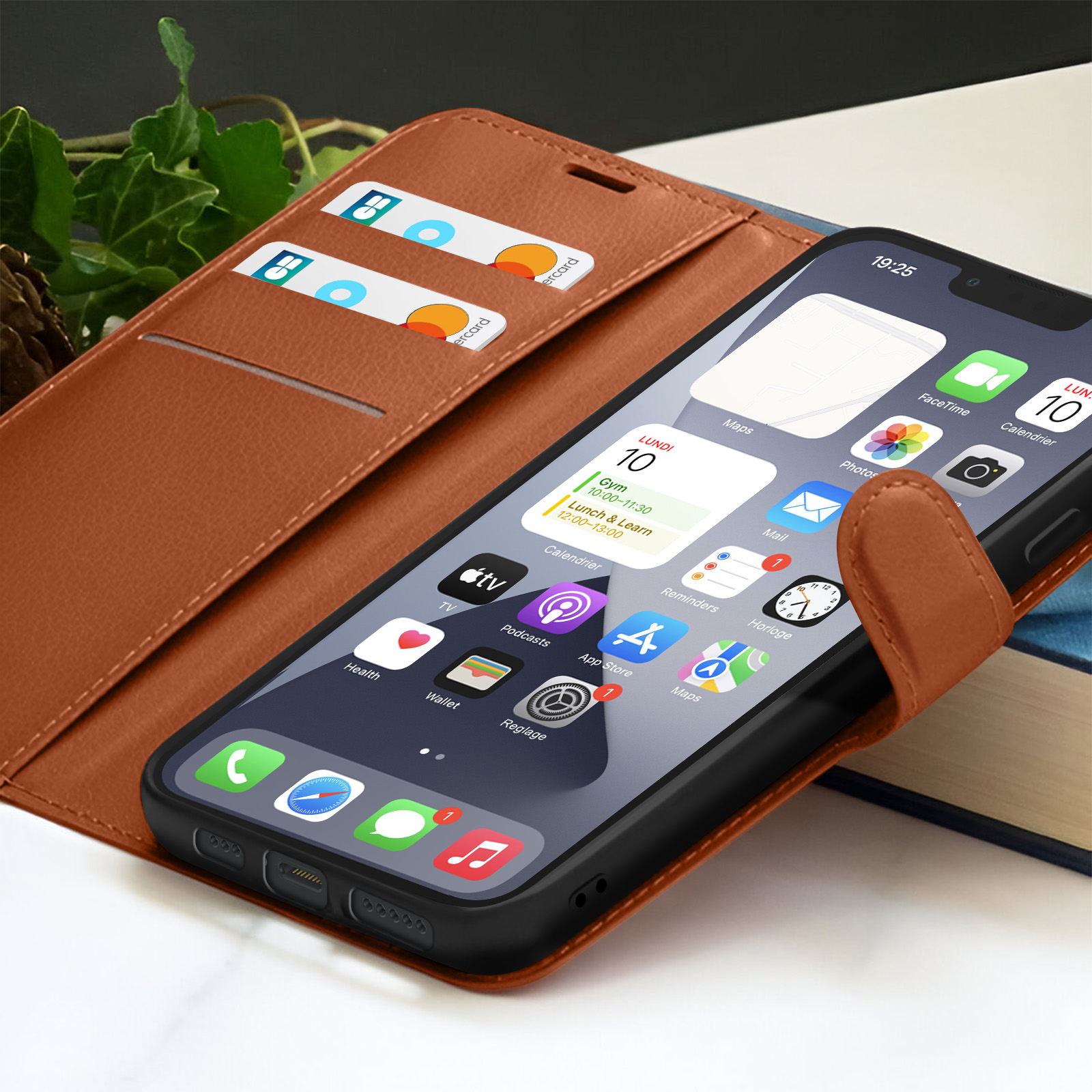 Een iPhone in een bruine lederen hoes is open en toont het startscherm. Creditcards zitten in een sleuf. Een boek staat op de achtergrond.