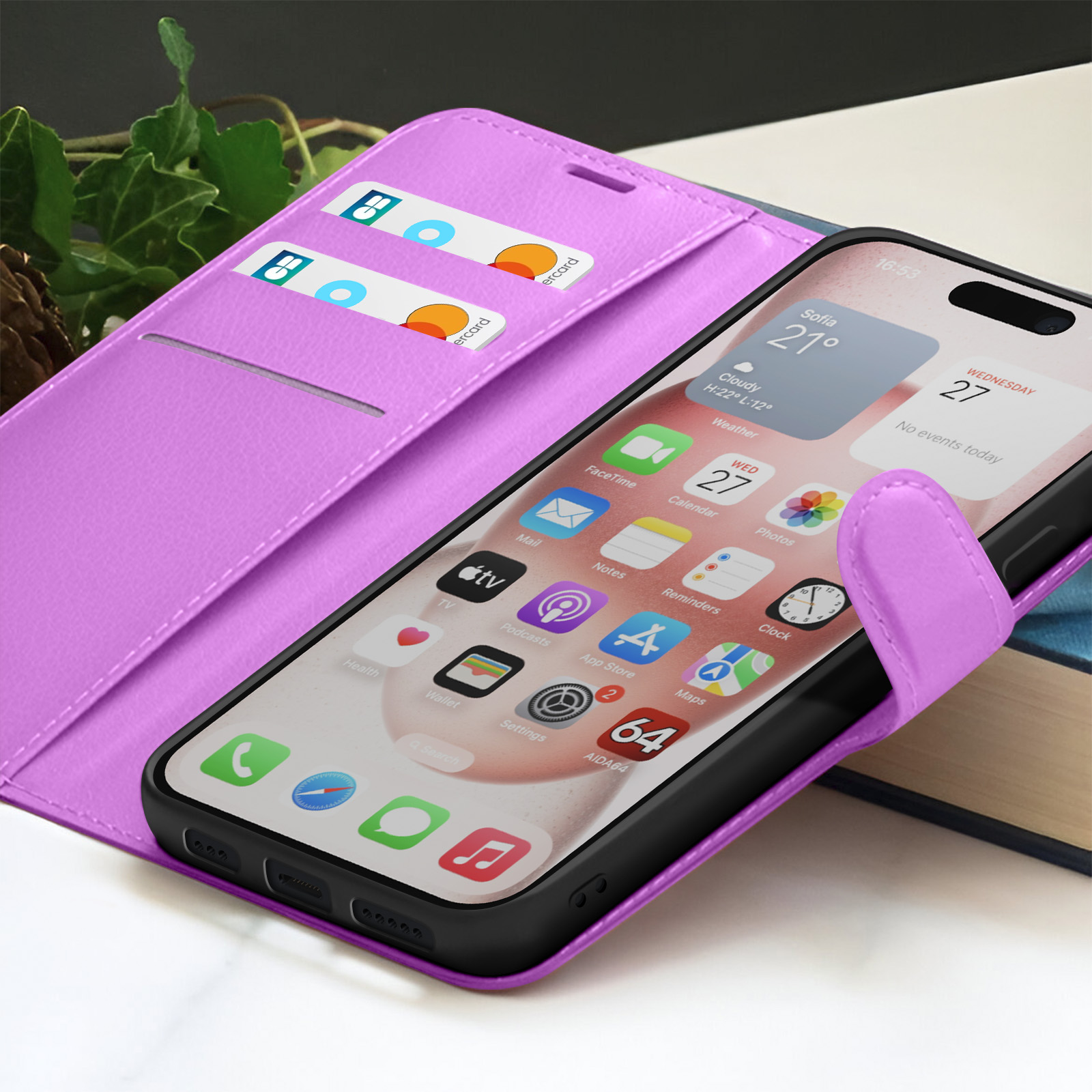 Un téléphone dans un étui violet est ouvert, affichant des applications. Des cartes de crédit sont dans une fente. L'arrière-plan est flou, avec des feuilles et un livre.