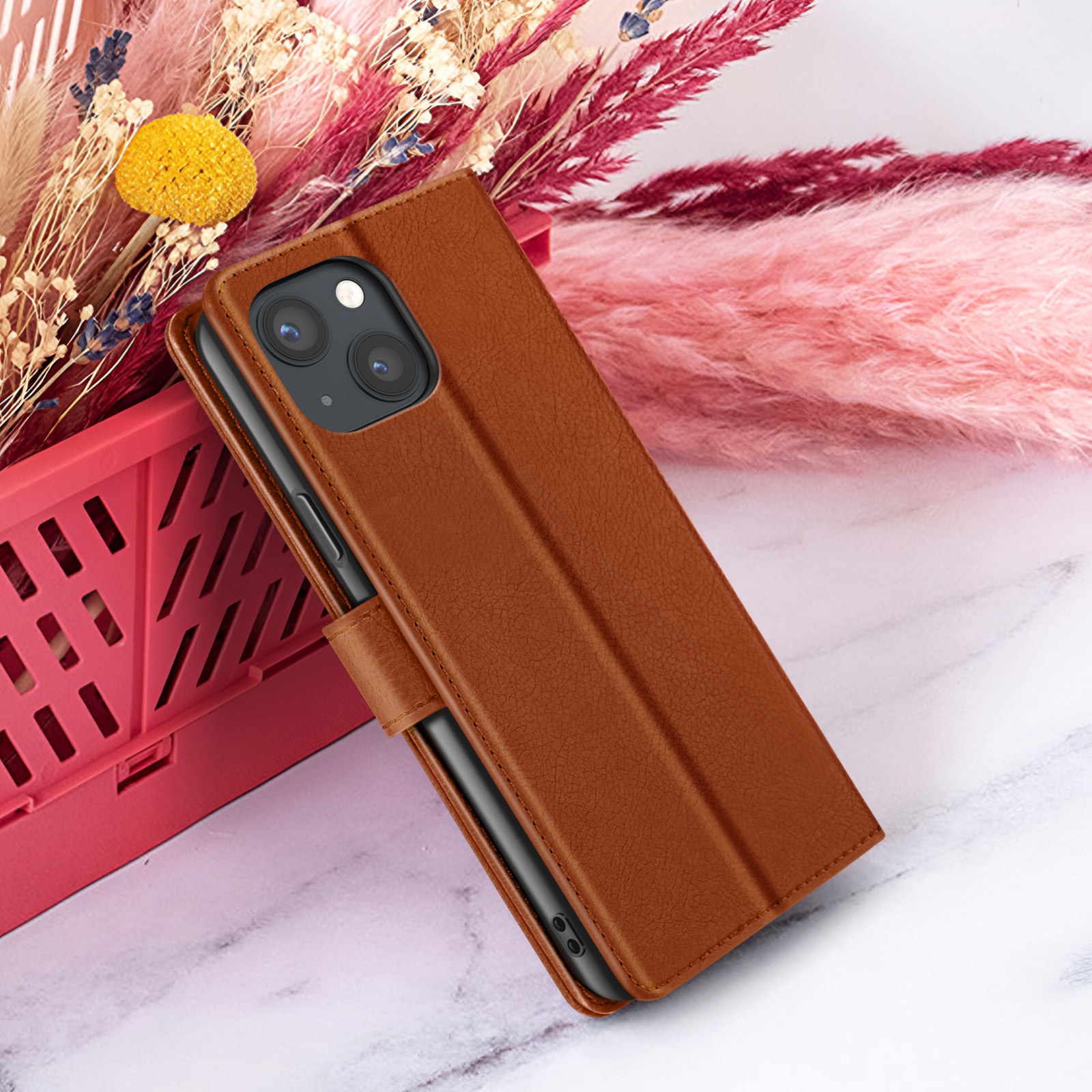 Bruine telefoonhoes met telefoon, op marmer. Roze bloemen en rode mand op de achtergrond.