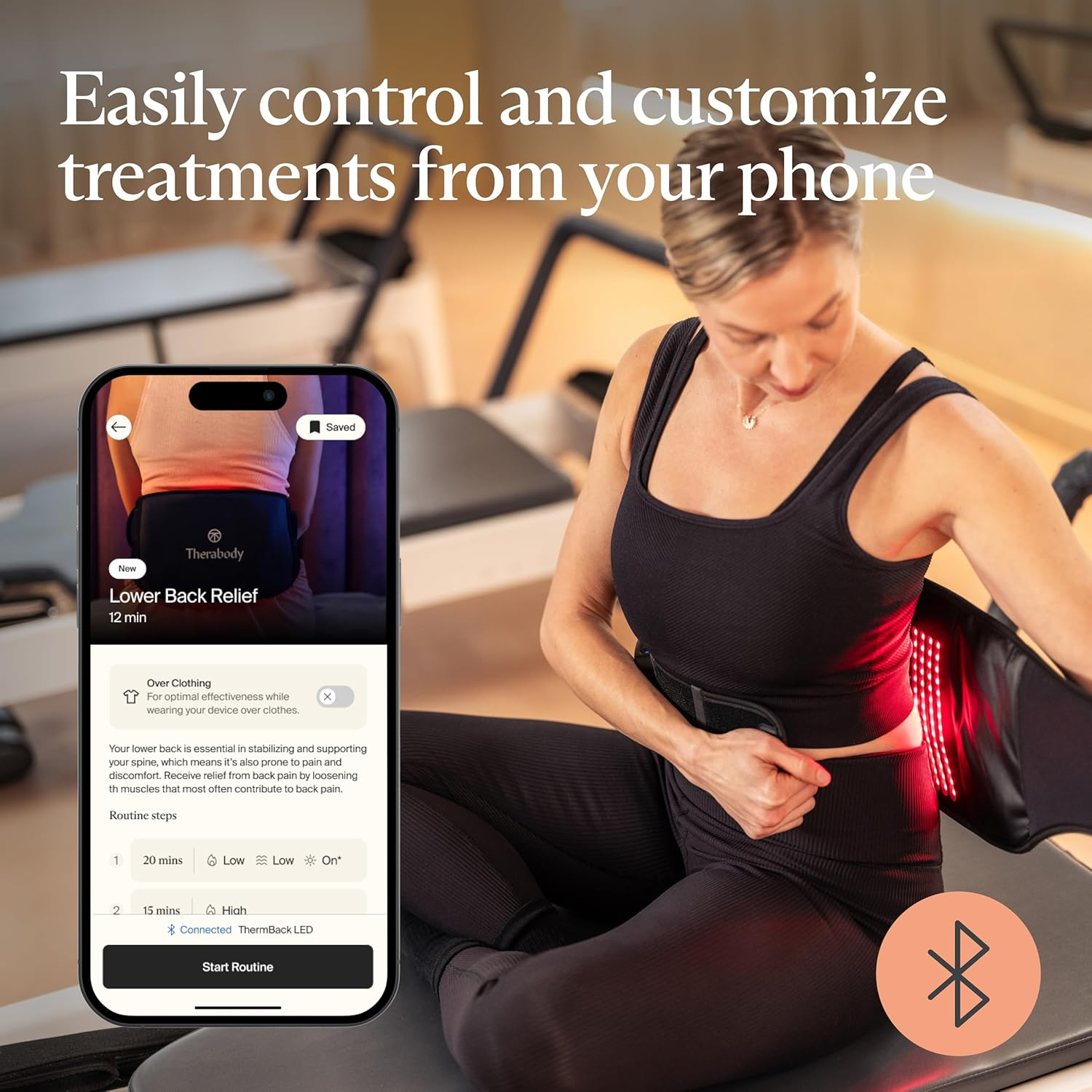 Mujer usando un teléfono para controlar un dispositivo para aliviar el dolor de espalda. El dispositivo emite luz roja y está envuelto alrededor de su espalda baja.