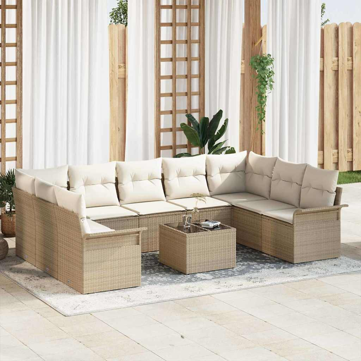Sofá seccional exterior con cojines crema y mesa de centro con tapa de cristal sobre alfombra estampada. Fondo: cortinas y valla de madera.