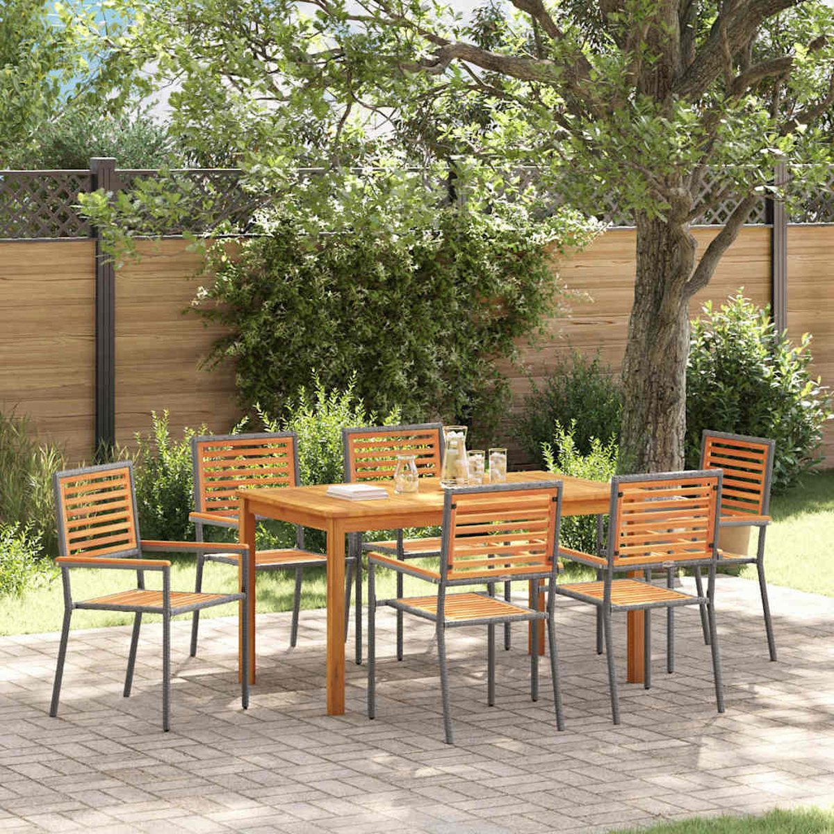 Juego de comedor al aire libre: mesa y sillas de madera en un patio de ladrillos, bajo un árbol. Fondo con cerca y vegetación.