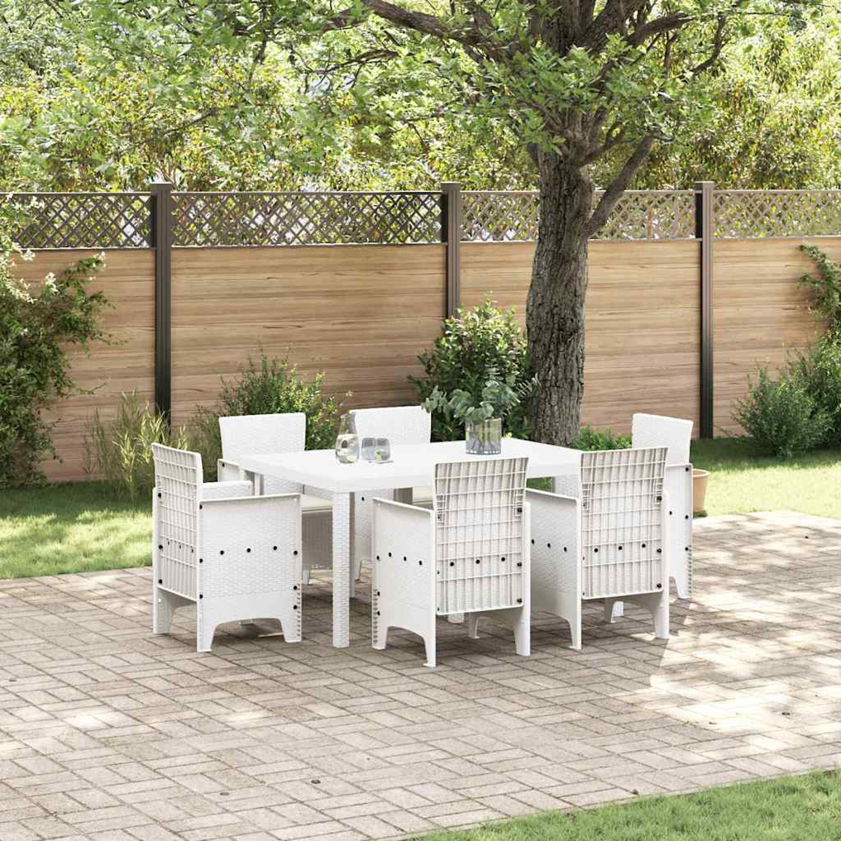 Un set da pranzo bianco per esterni con sei sedie è su un patio in mattoni. Una staccionata in legno e vegetazione creano una scena di giardino.