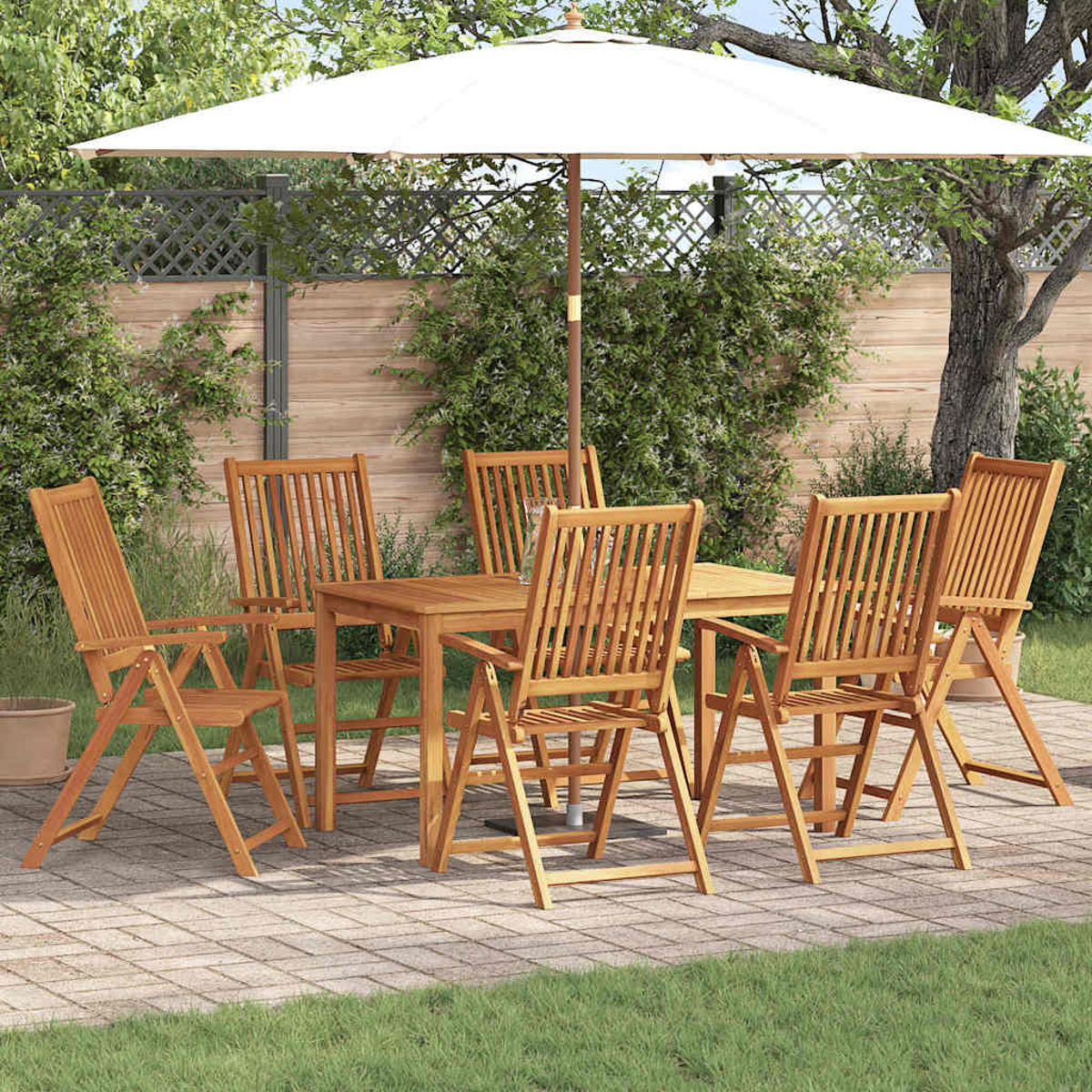 Essgarnitur im Freien mit Tisch, Stühlen und Sonnenschirm. Auf einer Terrasse, mit grünem Gras, Bäumen und Holzzaun im Hintergrund.