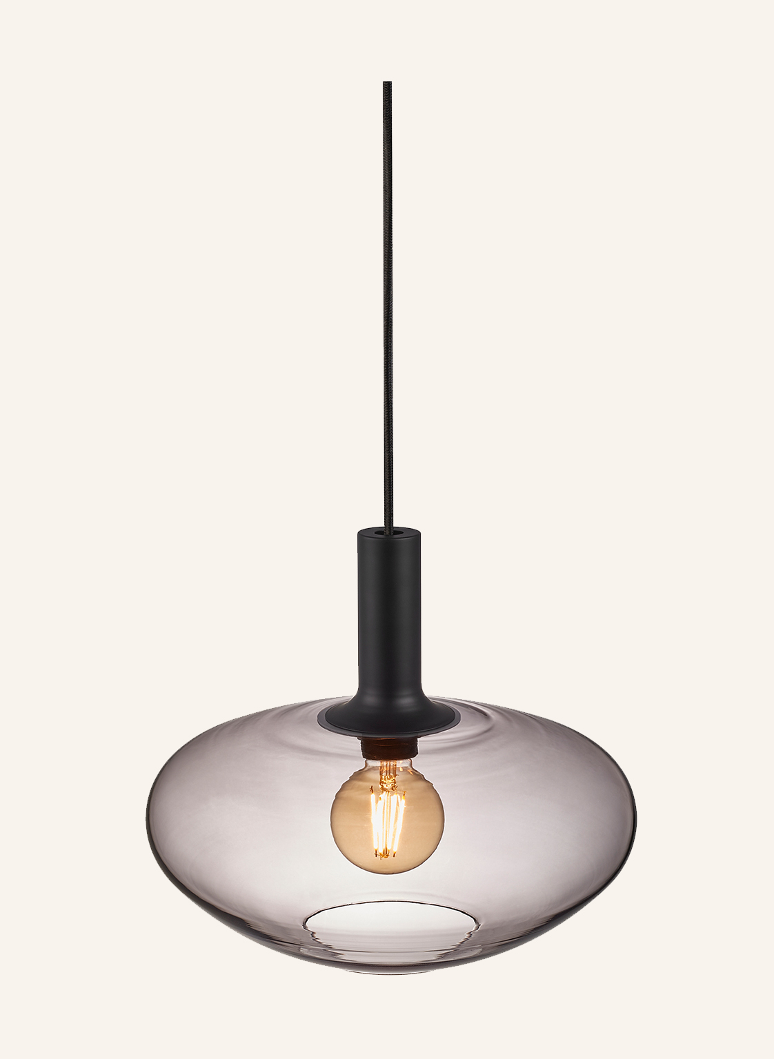 Une suspension moderne avec une armature en métal sombre et un abat-jour en verre fumé. Une ampoule chaude illumine le luminaire.