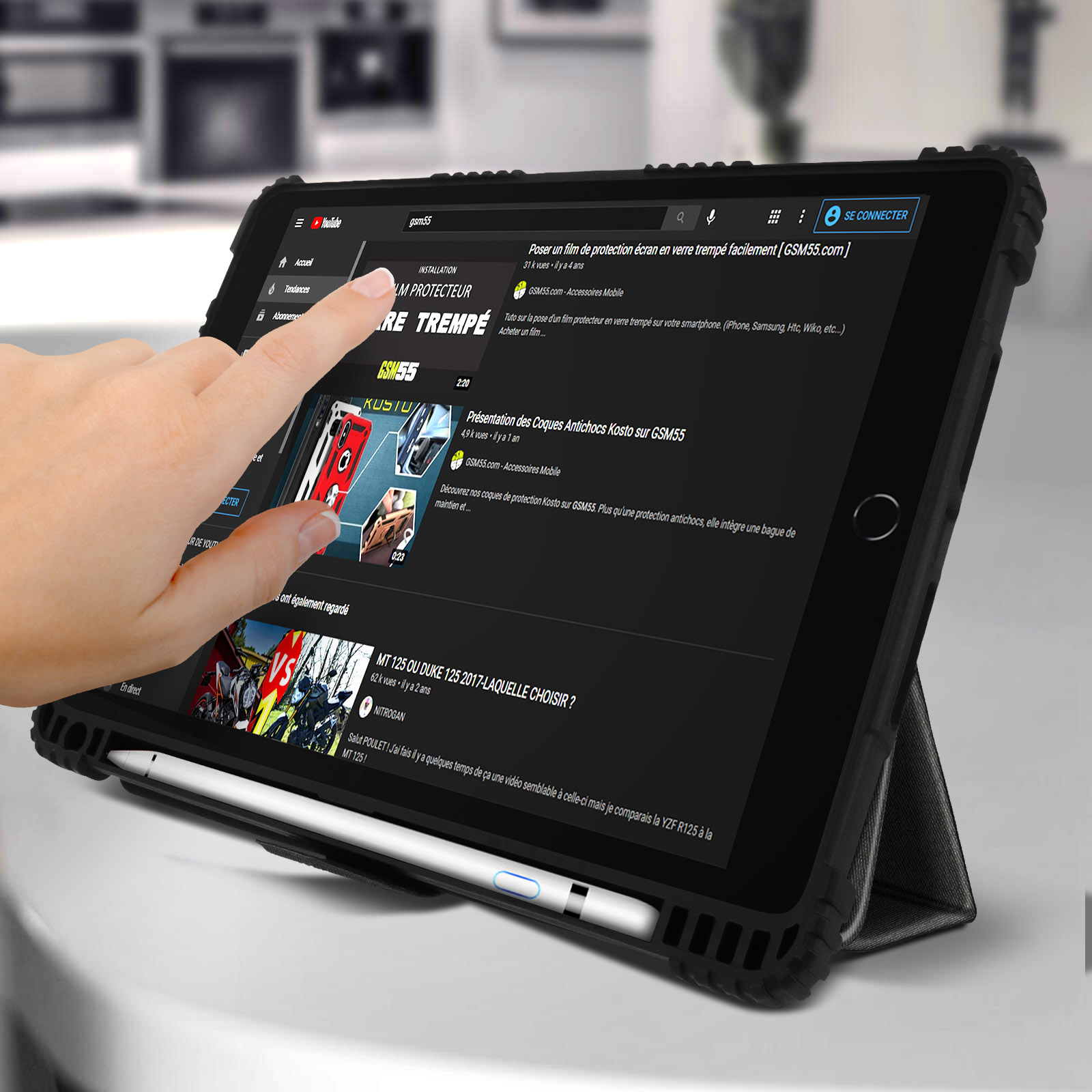 Una mano tocca lo schermo di un tablet che mostra un video di YouTube. Il video parla di protezioni per lo schermo.