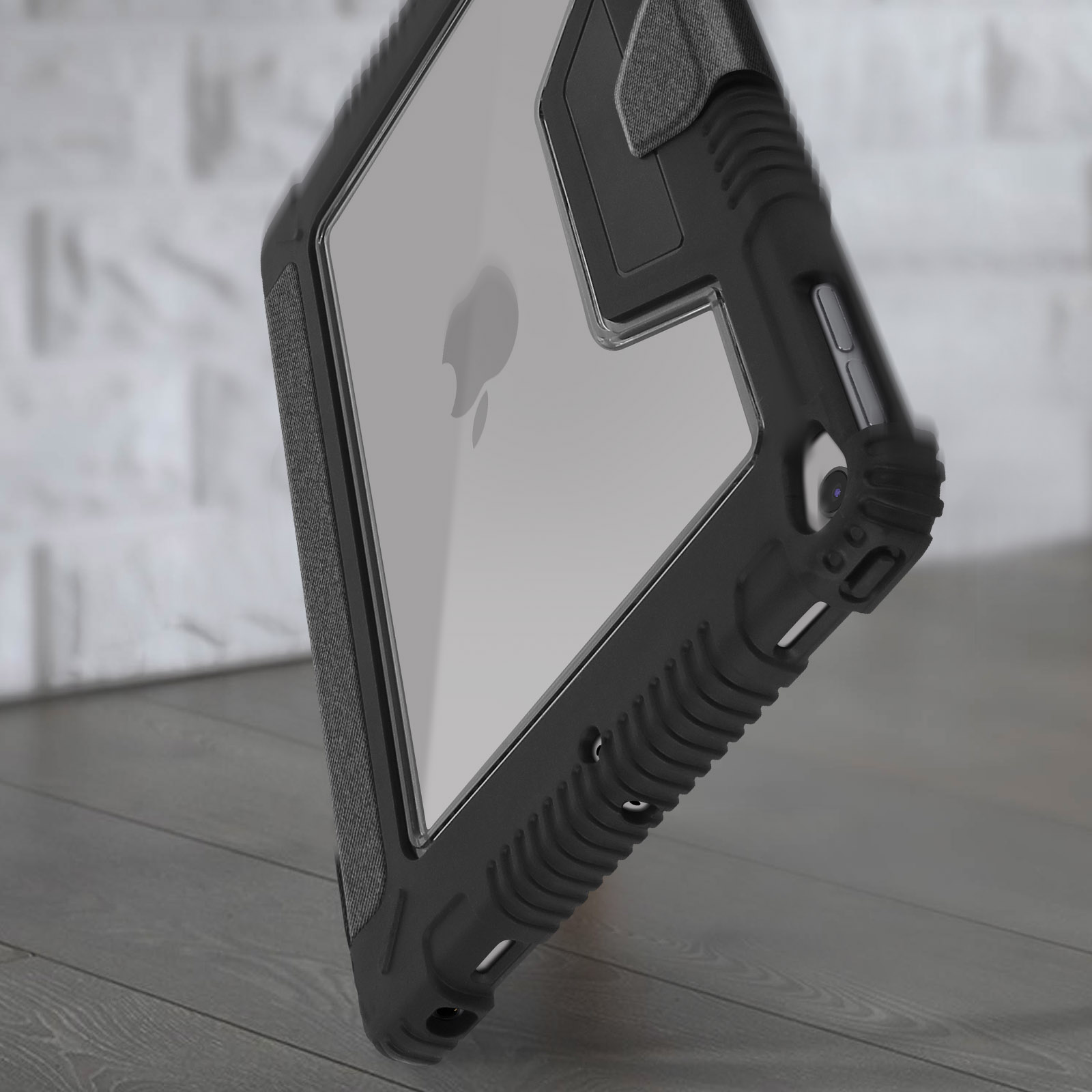 Un iPad in una custodia protettiva nera. La custodia ha un retro trasparente, che mostra il logo Apple. Lo sfondo è un muro di mattoni.