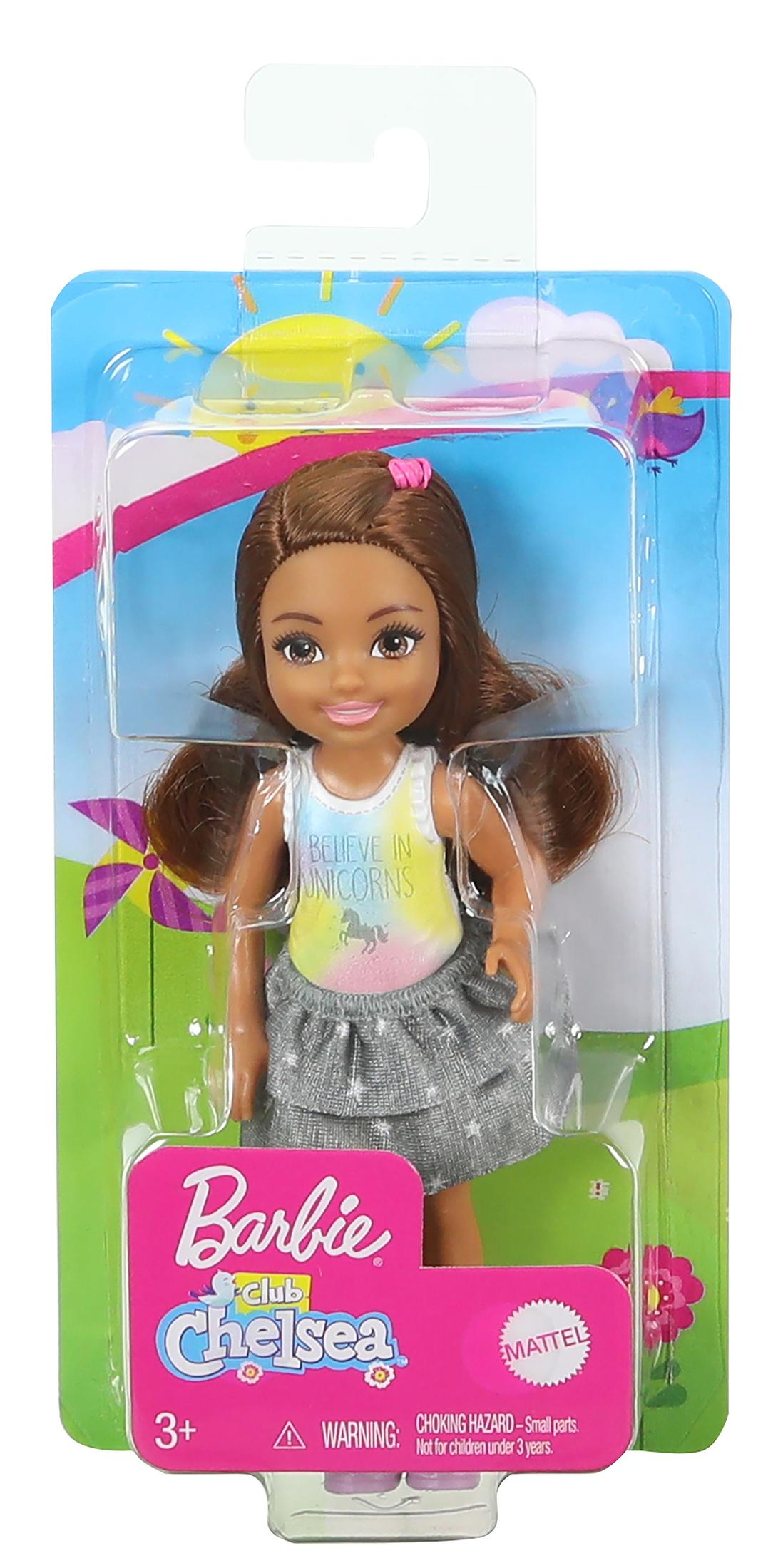 Eine Barbie Chelsea Puppe in Plastikverpackung. Die Puppe hat braune Haare und trägt ein Oberteil mit der Aufschrift "Believe in Unicorns" und einen grauen Rock.