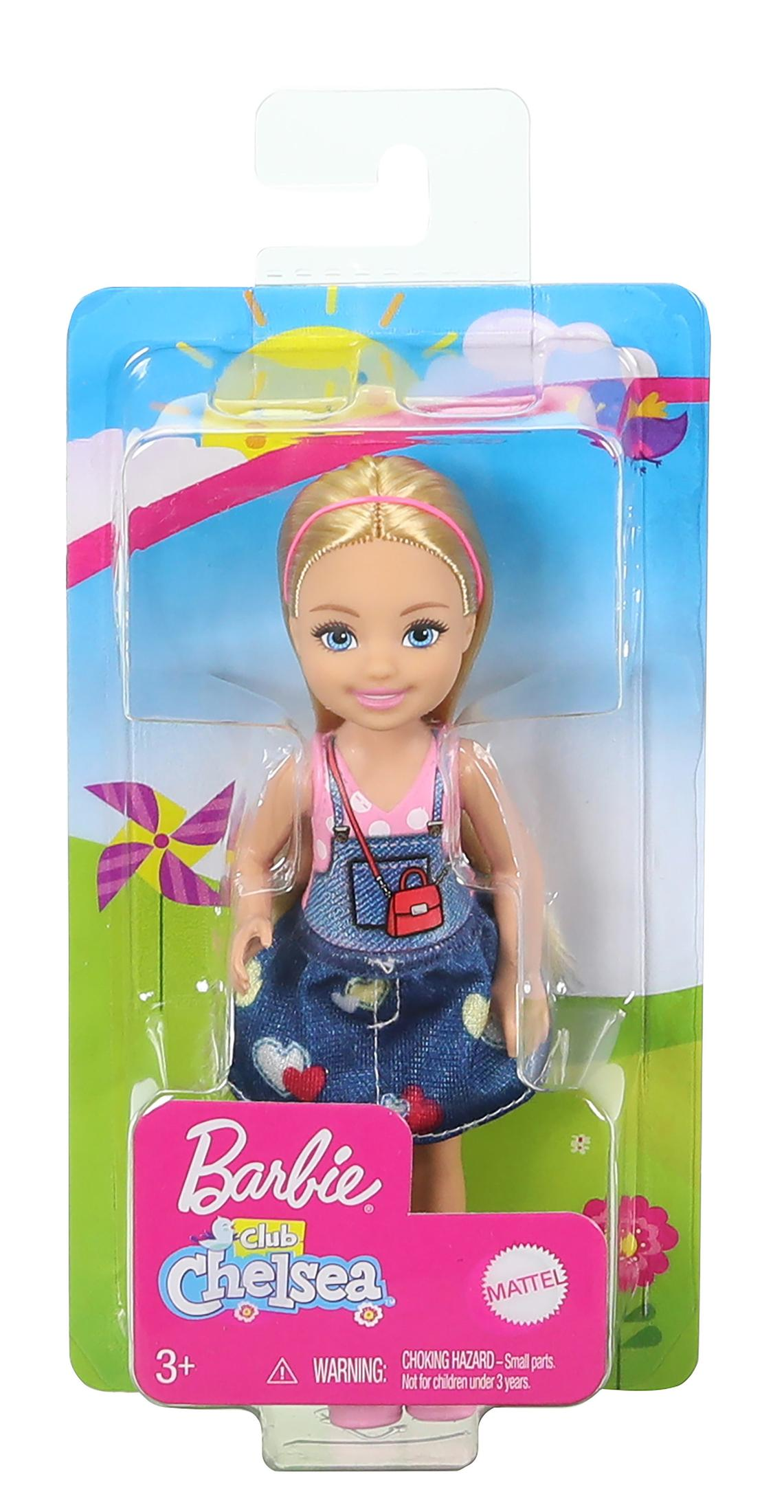 Barbie Chelsea-Puppe in Verpackung. Sie trägt eine Jeans-Latzhose, ein rosa Oberteil und eine rote Handtasche. Der Hintergrund zeigt einen sonnigen Tag.