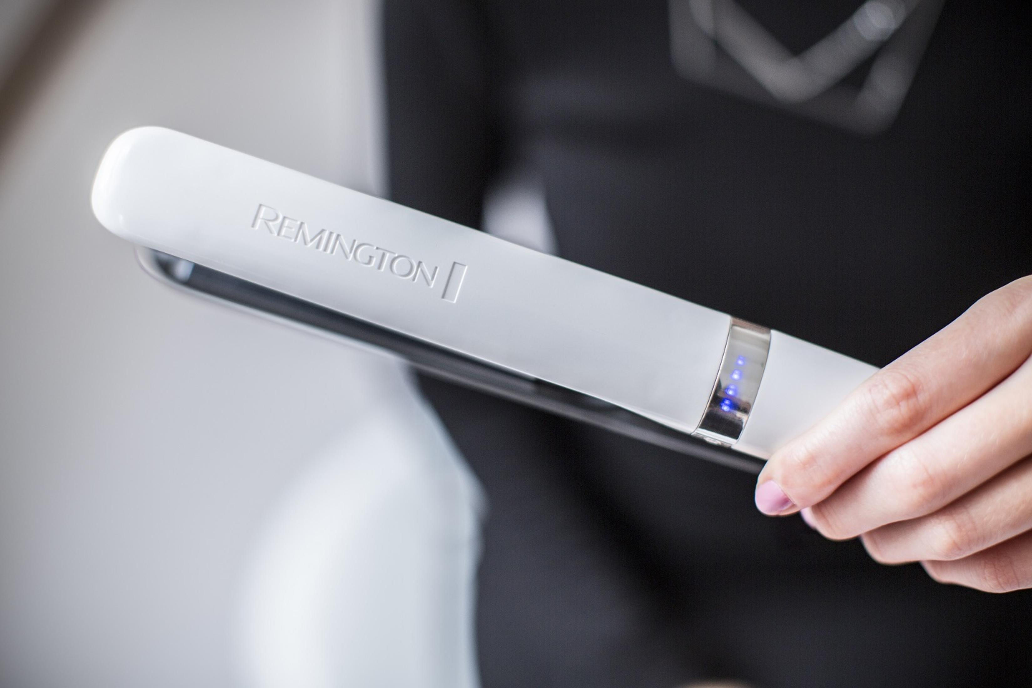 Eine weiße Remington Haarglättung wird von einer Person gehalten. Der Hintergrund ist verschwommen, mit einem schwarzen Oberteil.