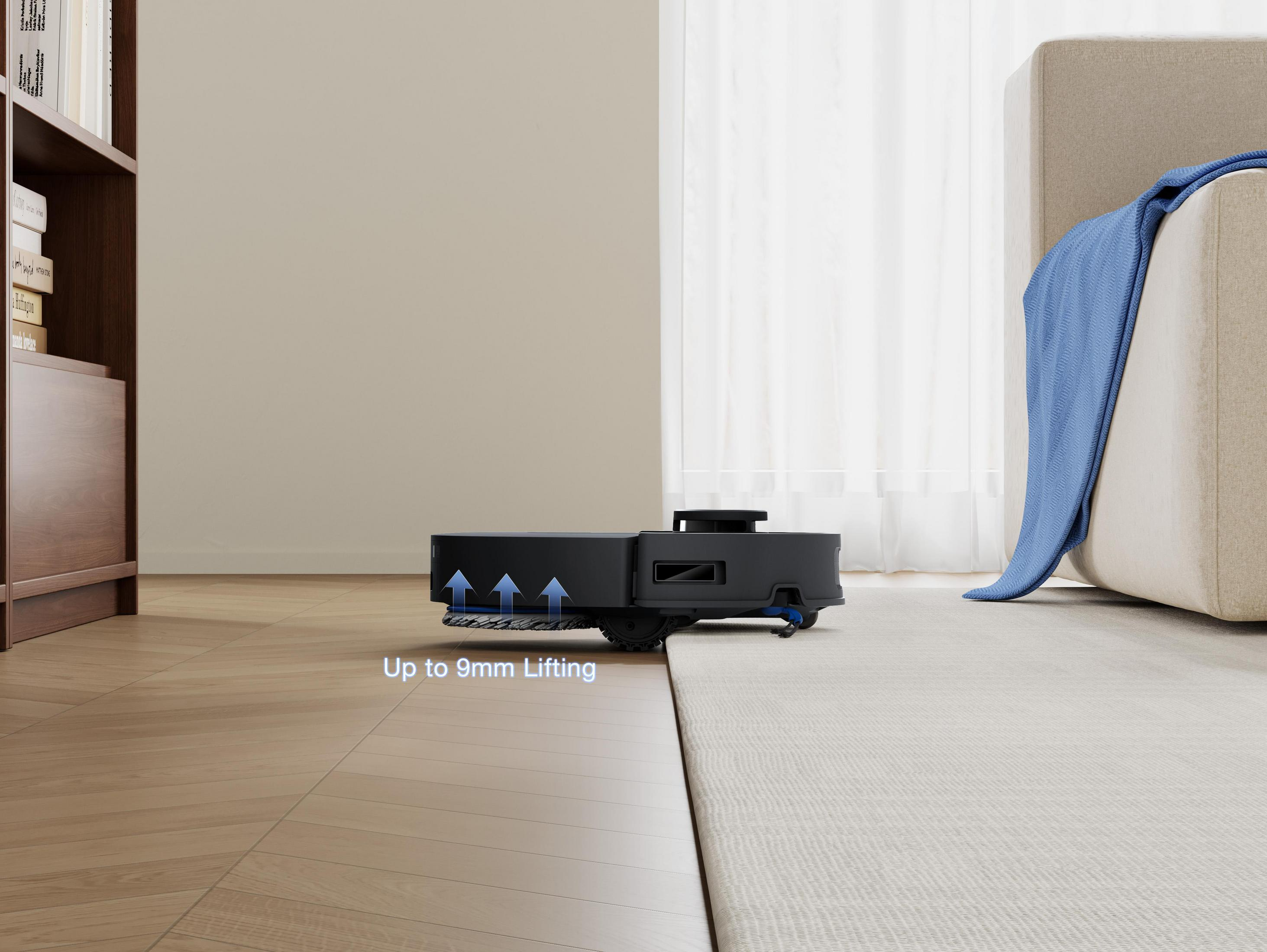 Ein schwarzer Roboter-Staubsauger auf einem hellen Teppich. Eine blaue Decke auf einem Sofa. Holzboden und ein Bücherregal.
