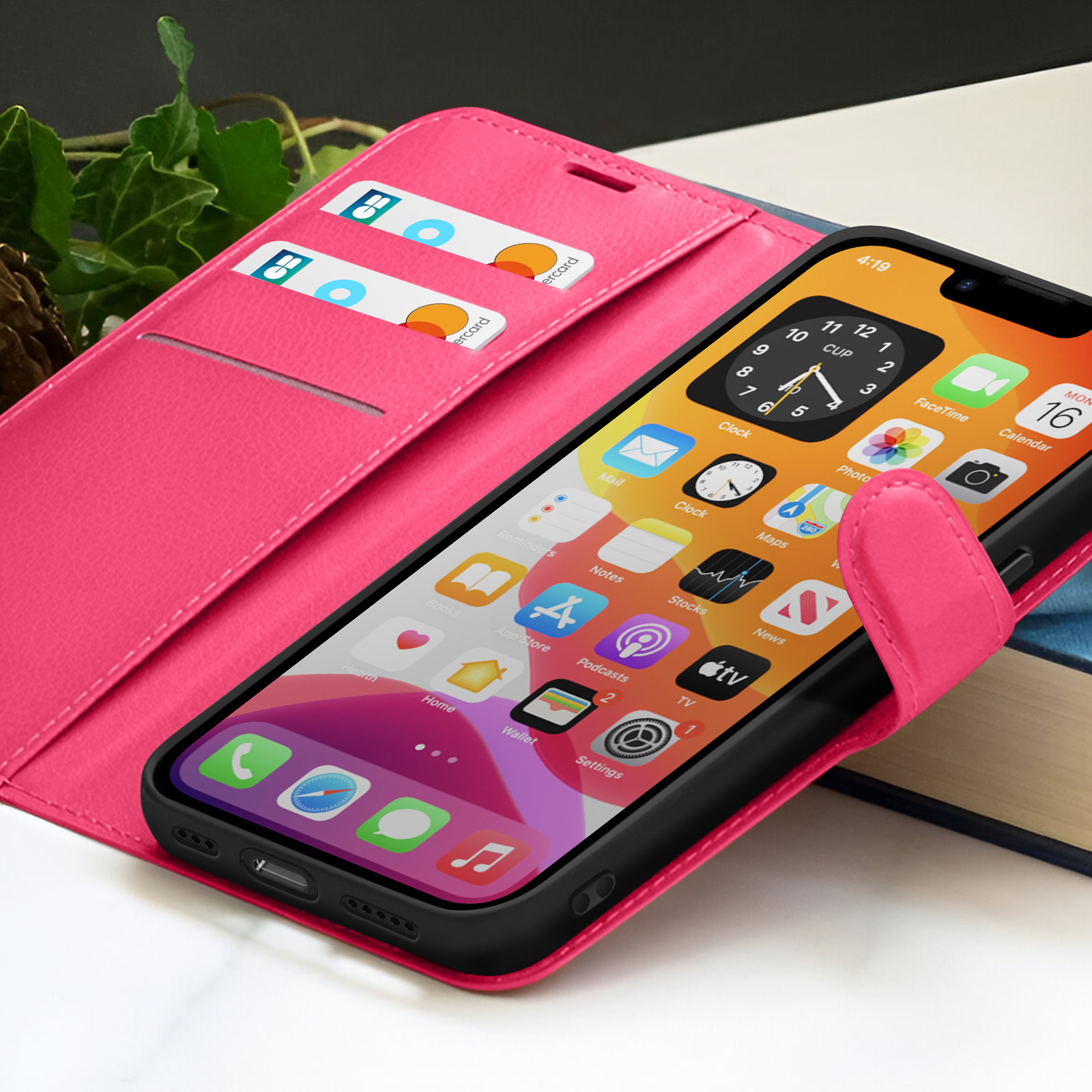 Een roze telefoonhoesje met een telefoon met app-iconen. Twee creditcards zitten in de hoes. Klimop op de achtergrond.