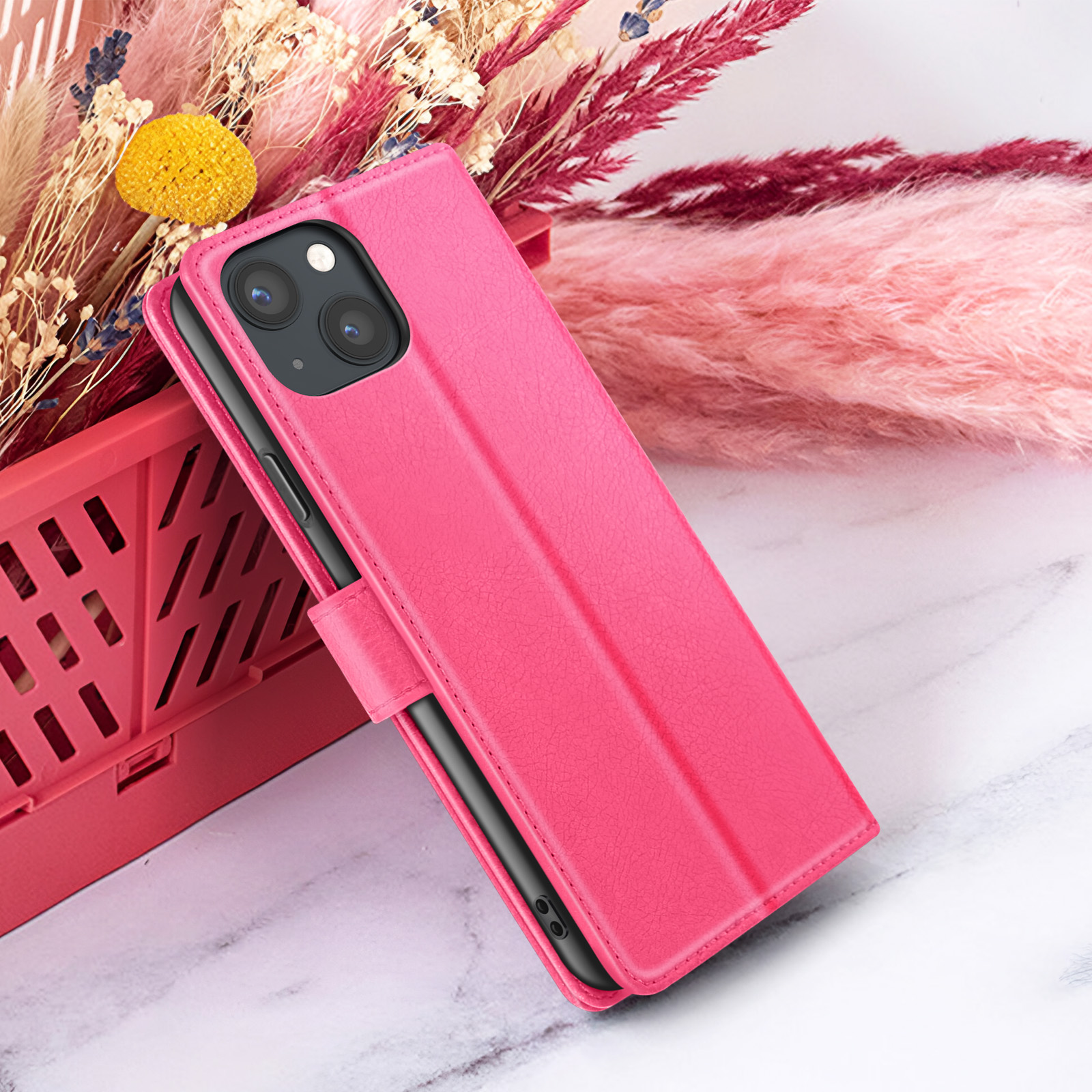 Roze telefoonhoes met telefoon. Achtergrond: bloemen in rode mand op marmeren oppervlak.