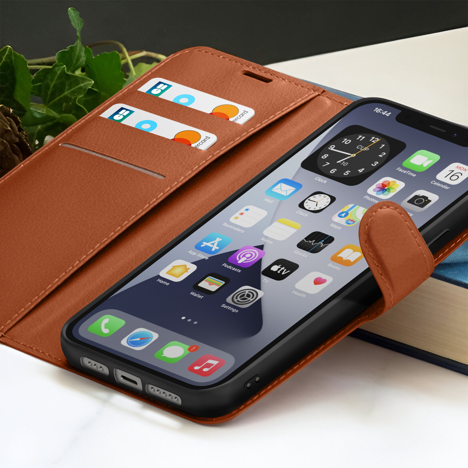 Een smartphone in een bruine leren hoes toont app-iconen. Creditcards zichtbaar in een zak. Een boek op de achtergrond.