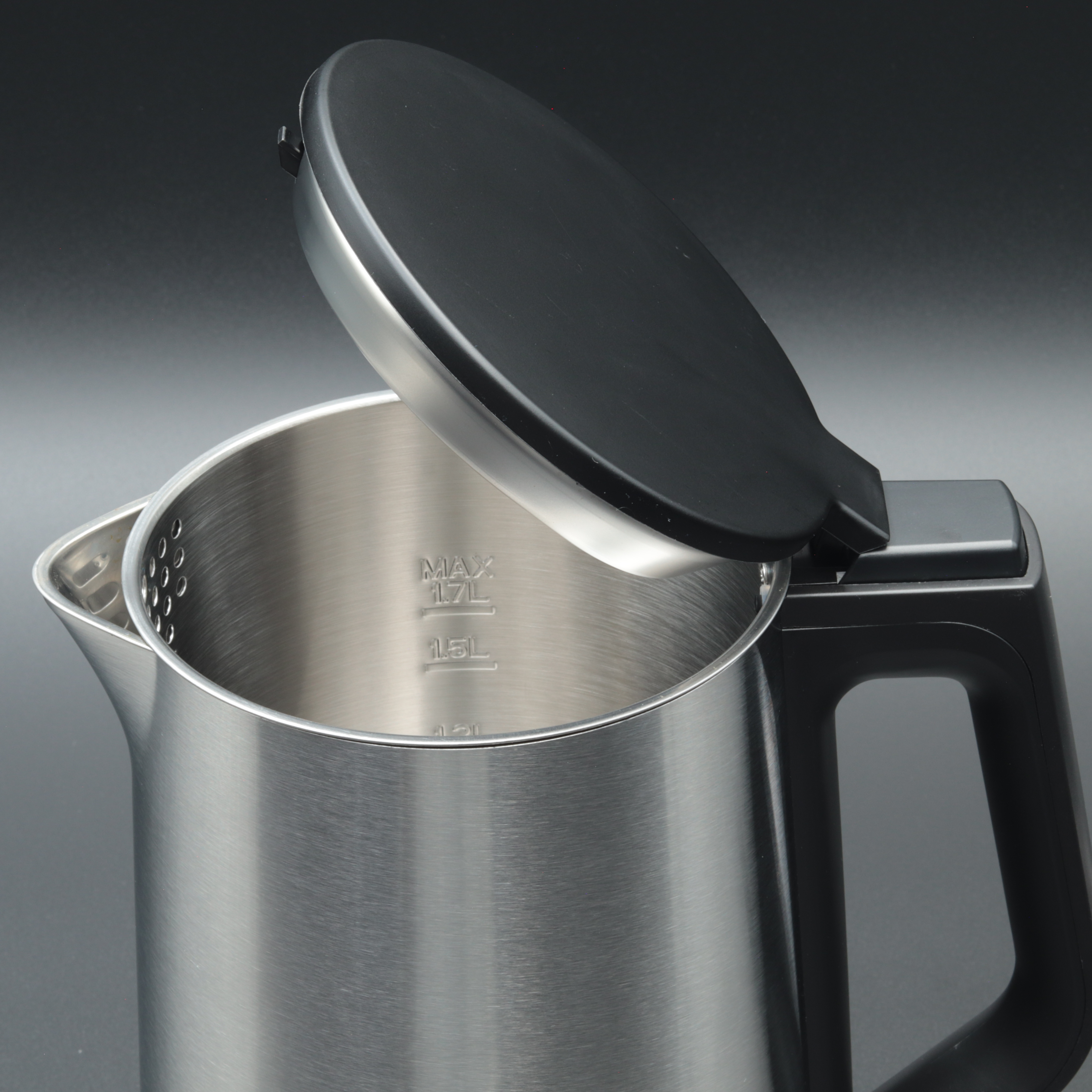 Ein Wasserkocher aus Edelstahl mit schwarzem Griff und Deckel ist teilweise geöffnet. Der Hintergrund ist grau.