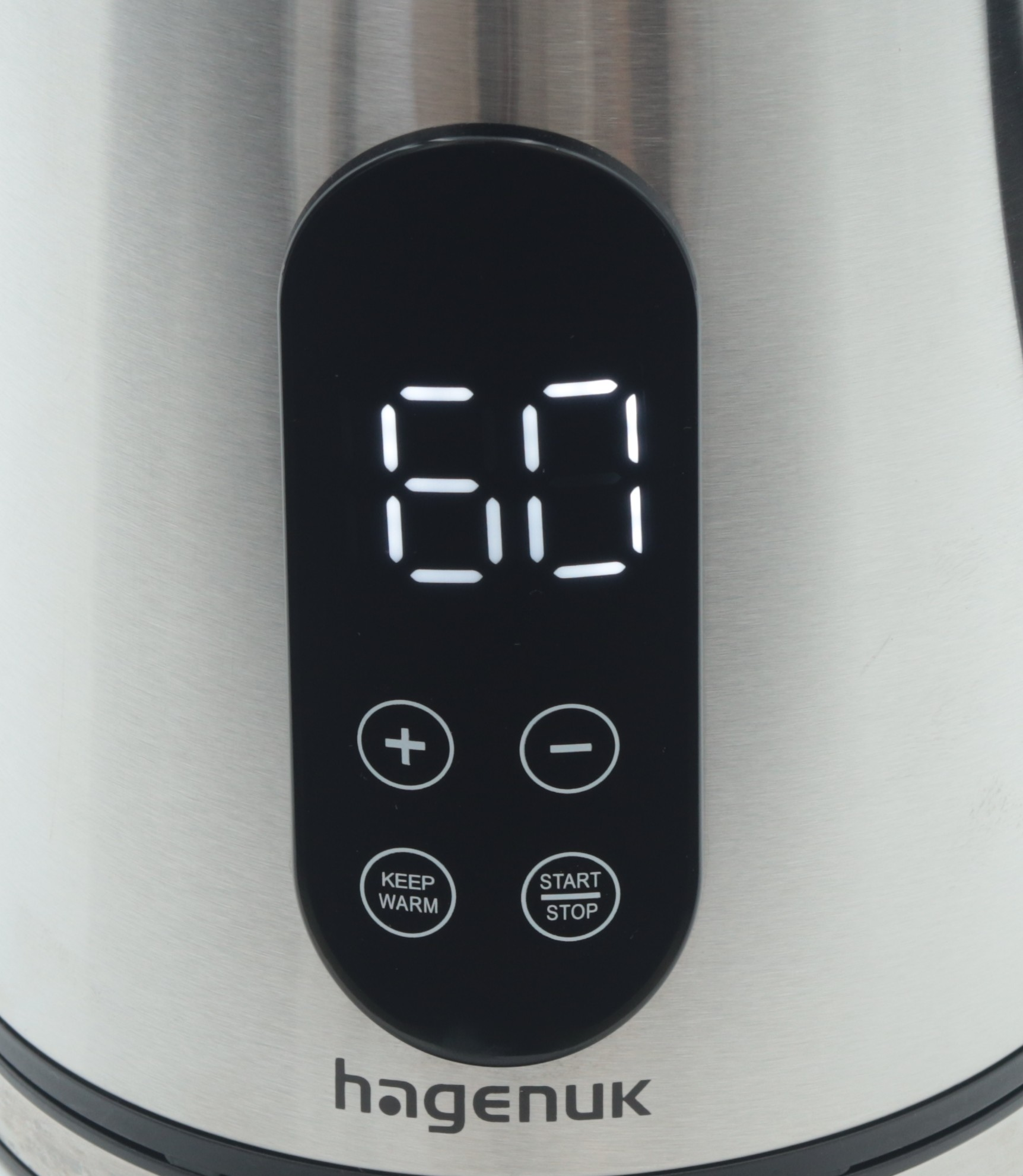 Nahaufnahme des Bedienfelds eines silbernen Wasserkochers mit Digitalanzeige 60. Tasten: +, -, Warmhalten, Start/Stopp. Marke: hagenuk.