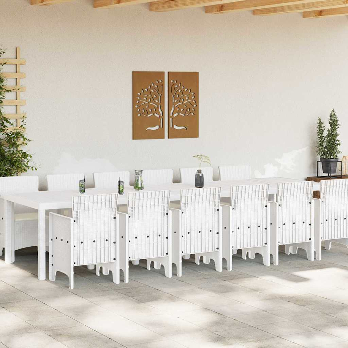 Essgruppe im Freien mit weißem Tisch und Stühlen. Wandkunst mit Baumdesign. Pflanzen auf dem Tisch und im Hintergrund.