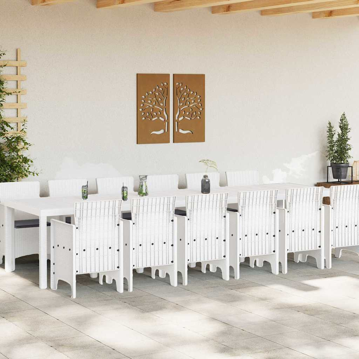 Juego de comedor al aire libre con sillas y mesa blancas. Arte mural marrón con diseño de árbol. Planta en maceta negra. Vigas de madera en el techo.