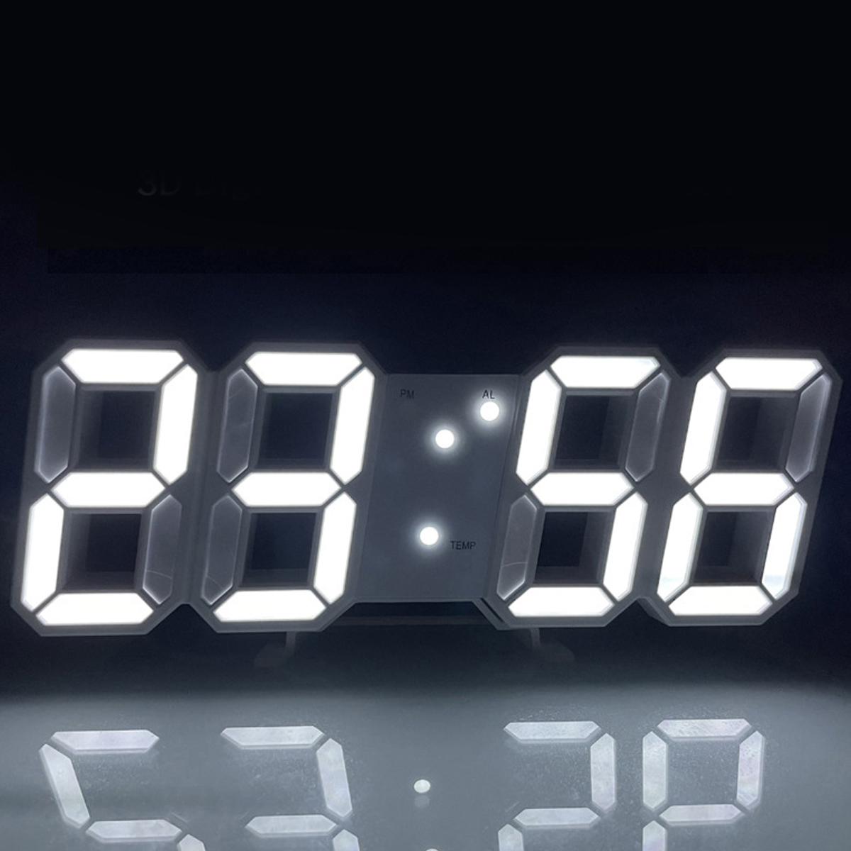 Digitaluhr zeigt 23:56 in hellem Weiß an. Drei kleine Lichter zeigen PM-, AL- und TEMP-Einstellungen an. Spiegelung darunter sichtbar.