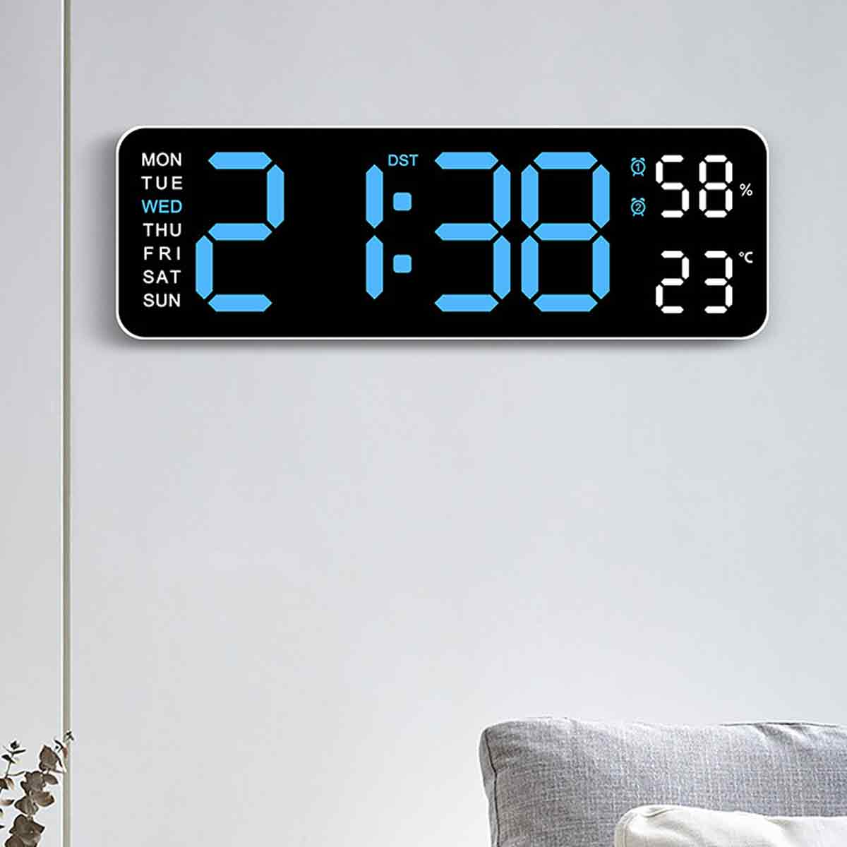 Eine Digitaluhr zeigt 2:38 Uhr mit Feuchtigkeits- und Temperaturanzeigen. Wochentage sind links aufgelistet. Die Uhr hängt an einer Wand.