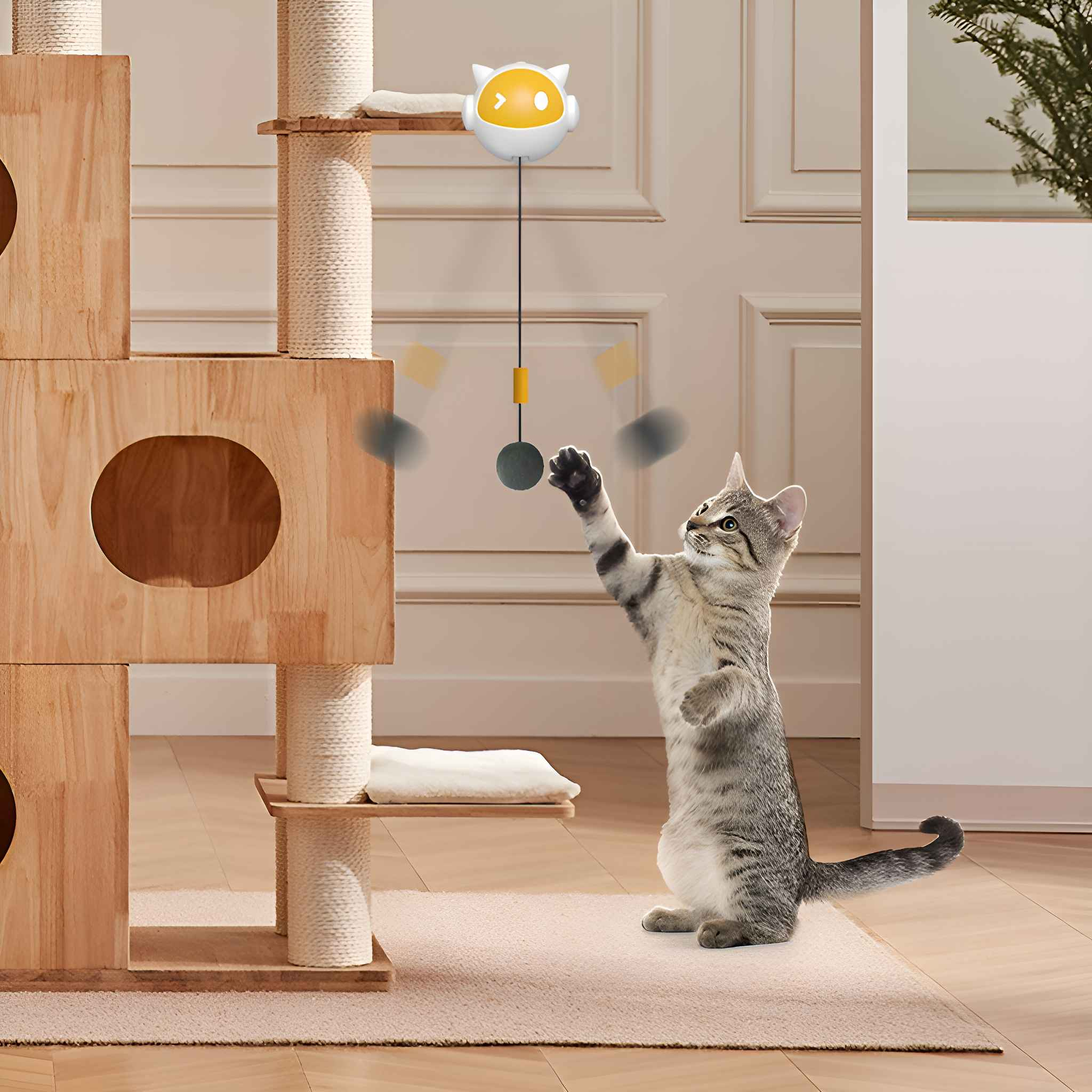 Eine Katze spielt mit einem Spielzeug, das an einem Kratzbaum hängt. Die Katze ist grau und weiß. Das Spielzeug ist ein Ball.