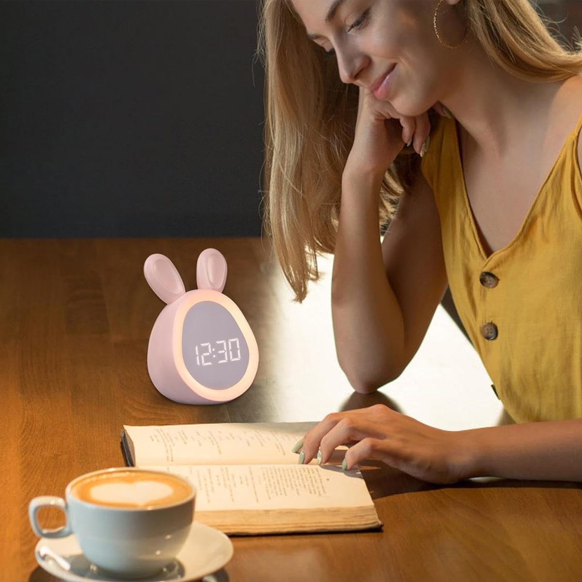 Eine Frau mit blonden Haaren liest ein Buch an einem Holztisch. Eine hasenförmige Uhr zeigt 12:30 an. Eine Tasse Kaffee steht daneben.