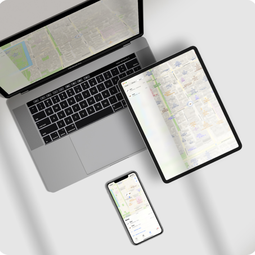 Laptop, Tablet und Smartphone zeigen Karten. Der Laptop ist geöffnet. Das Tablet ist rechts. Das Telefon ist darunter.