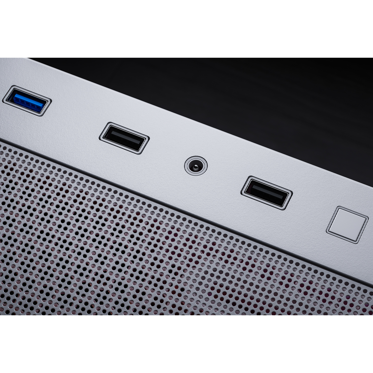 Detail des silbernen Computergehäuses mit USB-Anschlüssen, Audioanschluss und Einschaltknopf. Perforiertes Metallgitter unten.