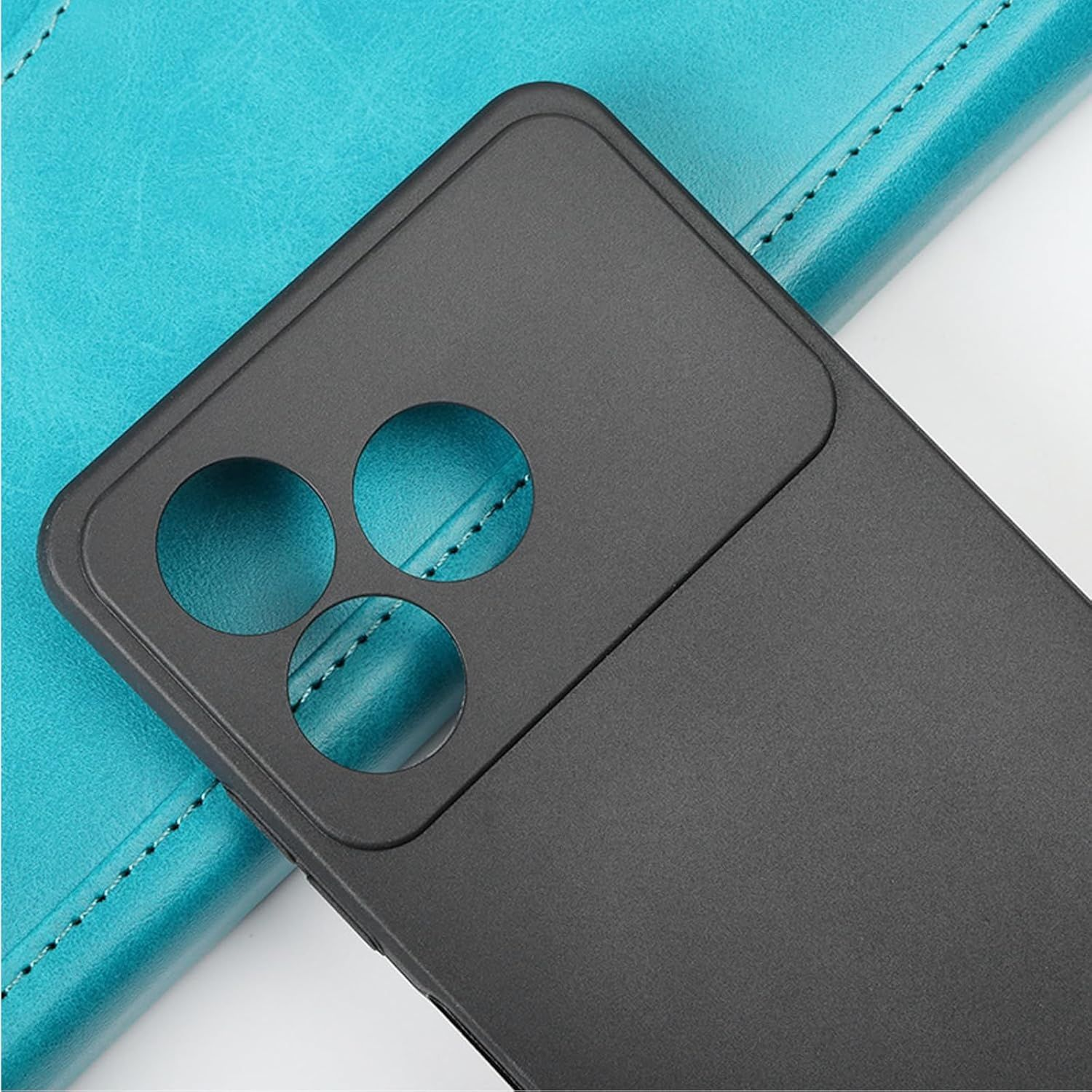 Funda negra para teléfono con tres recortes redondos para la cámara, apoyada sobre una superficie de cuero turquesa con borde cosido.