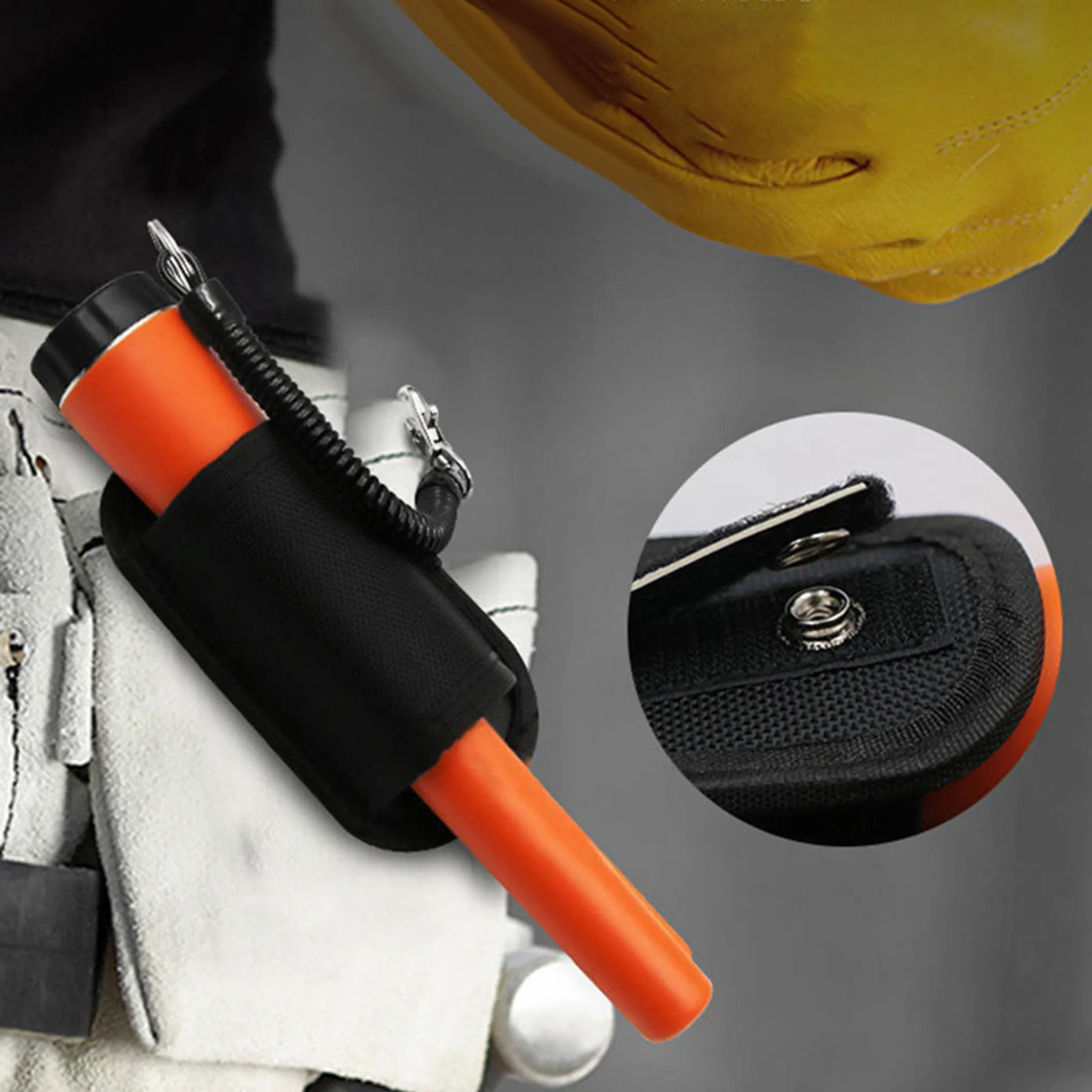 Ein orangefarbener Metalldetektor in einer schwarzen Halterung. Ein Teil einer gelben Hand ist im Hintergrund.