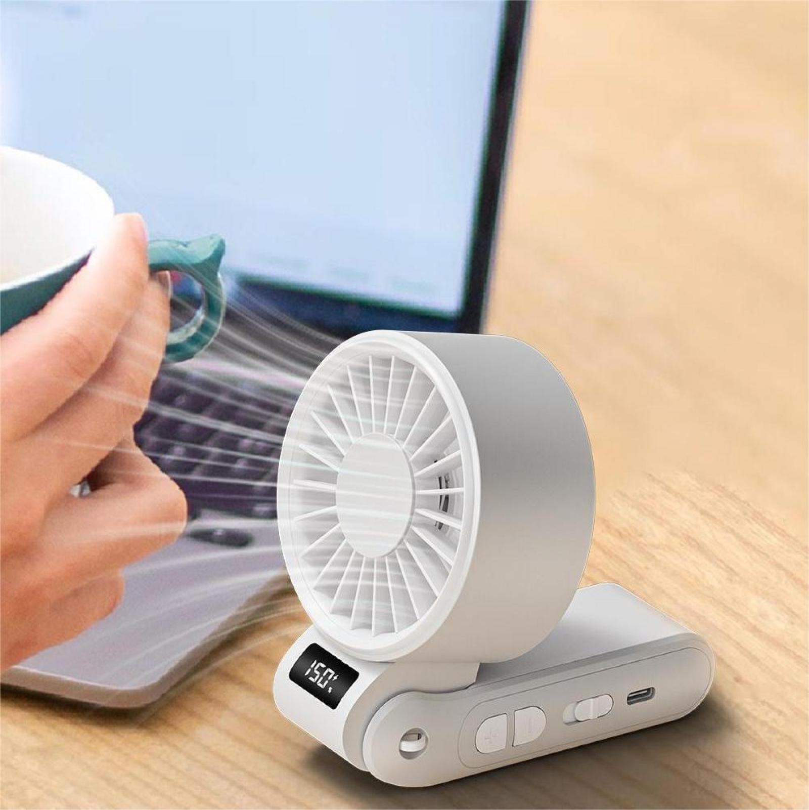 Ein weißer tragbarer Ventilator mit digitaler Anzeige (150%) steht auf einem Holztisch. Eine Hand hält einen Becher in der Nähe eines Laptops.
