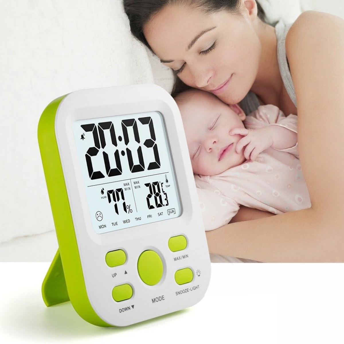 Eine Digitaluhr zeigt Zeit, Luftfeuchtigkeit und Temperatur an. Im Hintergrund schlafen eine Frau und ein Baby friedlich.