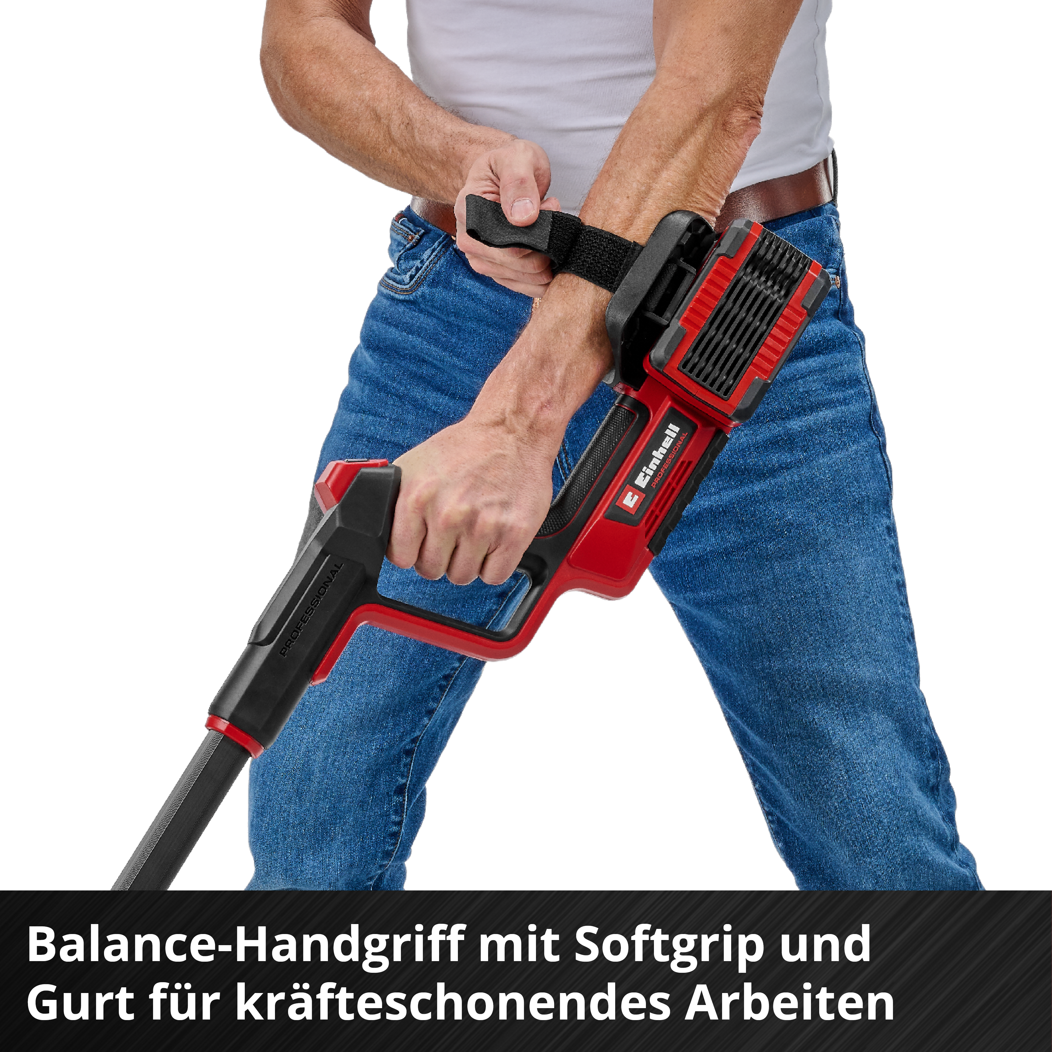 Une personne tient un outil de jardinage rouge et noir. L'outil a une sangle autour du bras. La personne porte un jean et une chemise blanche.