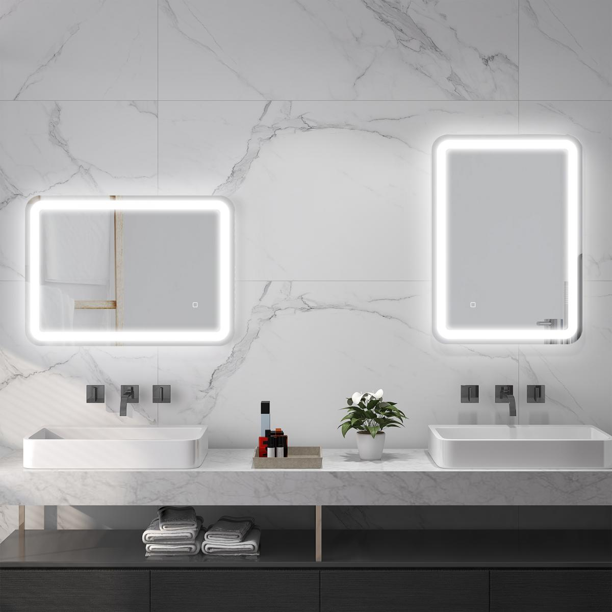 Ein modernes Badezimmer mit zwei beleuchteten Spiegeln, Waschbecken und Marmorwänden. Enthält Handtücher, Toilettenartikel und eine Pflanze.