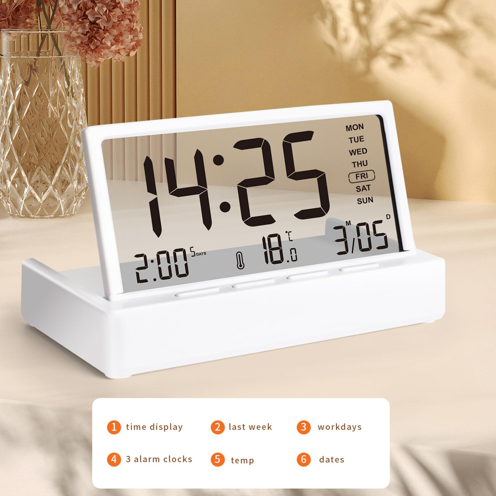 Ein weißer digitaler Wecker zeigt Uhrzeit, Datum und Temperatur an. Dekorative Blumen stehen links in einer Vase.