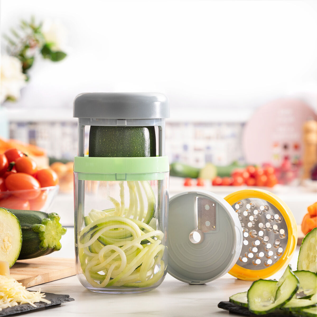 Uno spiralizzatore per zucchine con zucchine all'interno e spirali di zucchine. Altre verdure e strumenti sullo sfondo.
