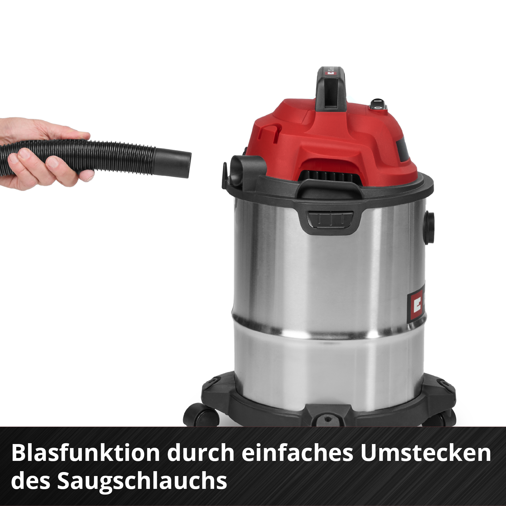 Eine Hand hält einen schwarzen Schlauch in der Nähe eines silbernen und roten Staubsaugers. Der Schlauch soll angeschlossen werden.