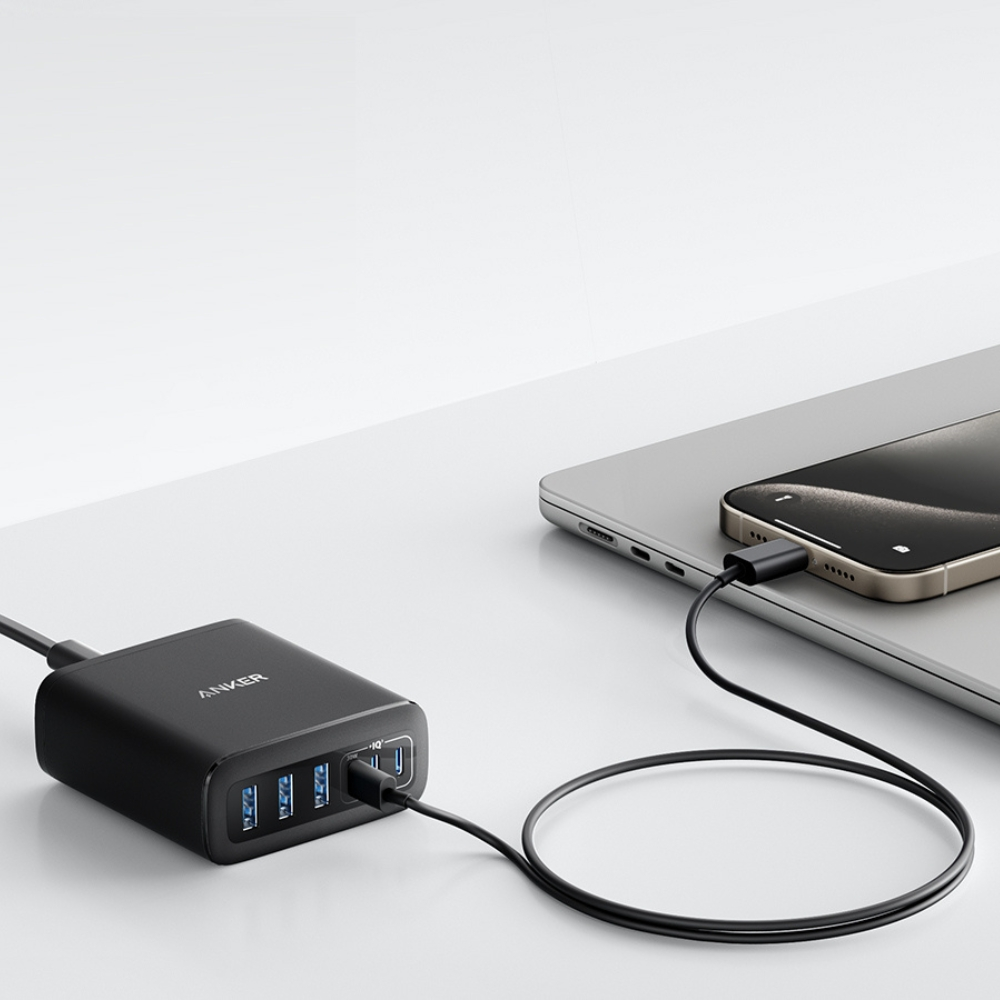 Una stazione di ricarica Anker nera con più porte USB, collegata a un telefono su un laptop tramite un cavo nero.