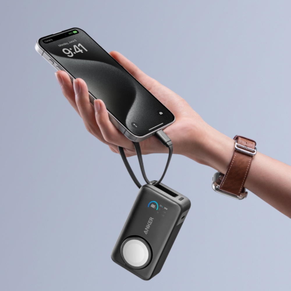 Ręka trzyma telefon ładujący się z czarnego power banku Anker. Na nadgarstku jest zegarek. Tło to jasnoniebieski gradient.