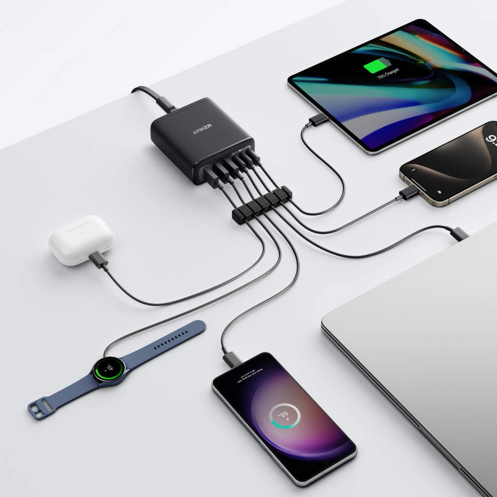 Una stazione di ricarica Anker nera con più dispositivi collegati: tablet, telefono, laptop, smartwatch, auricolari e un telefono.