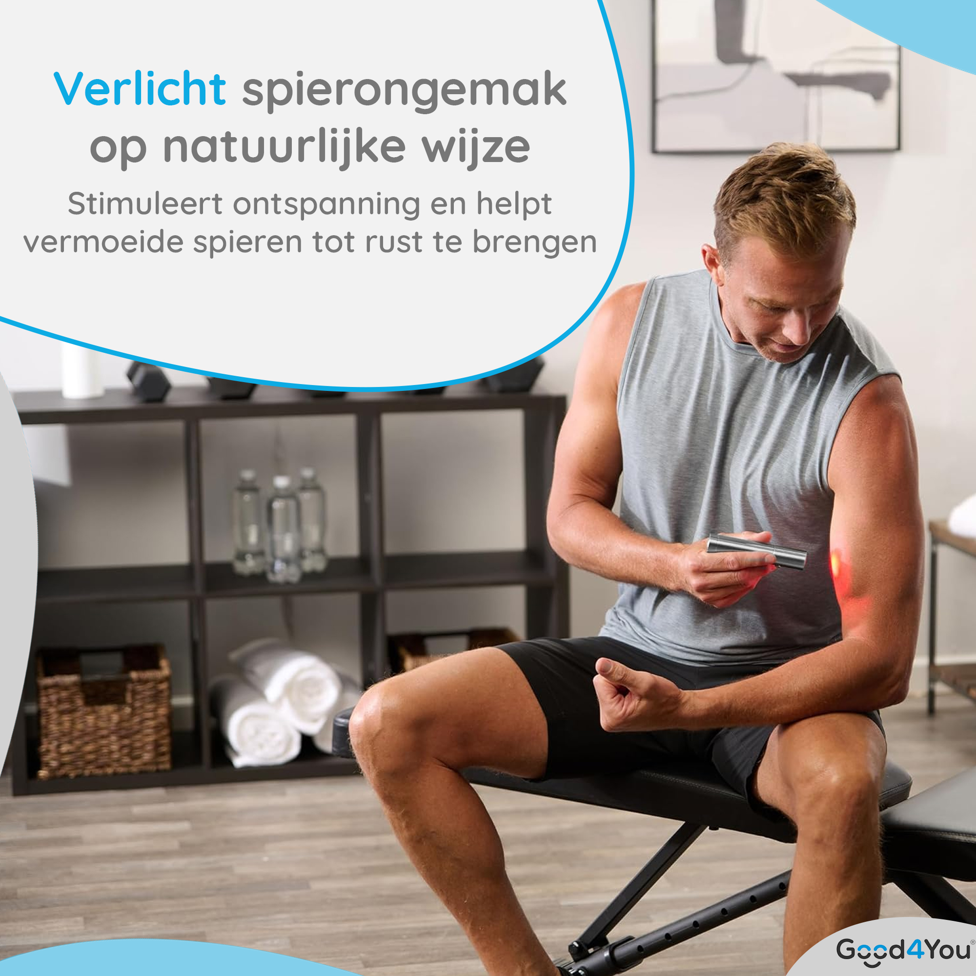 Ein Mann verwendet ein Rotlichttherapiegerät an seinem Arm. Er trägt ein graues Tanktop. Der Hintergrund umfasst Regale und Handtücher.