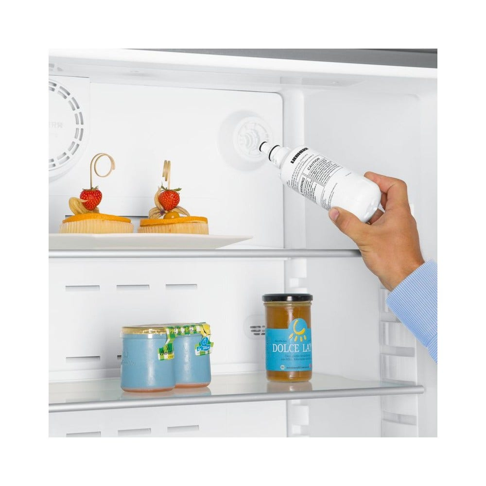 In einem Kühlschrank hält eine Hand einen weißen Filter. Es gibt Desserts, Gläser mit Lebensmitteln und einen Wasserfiltermechanismus.