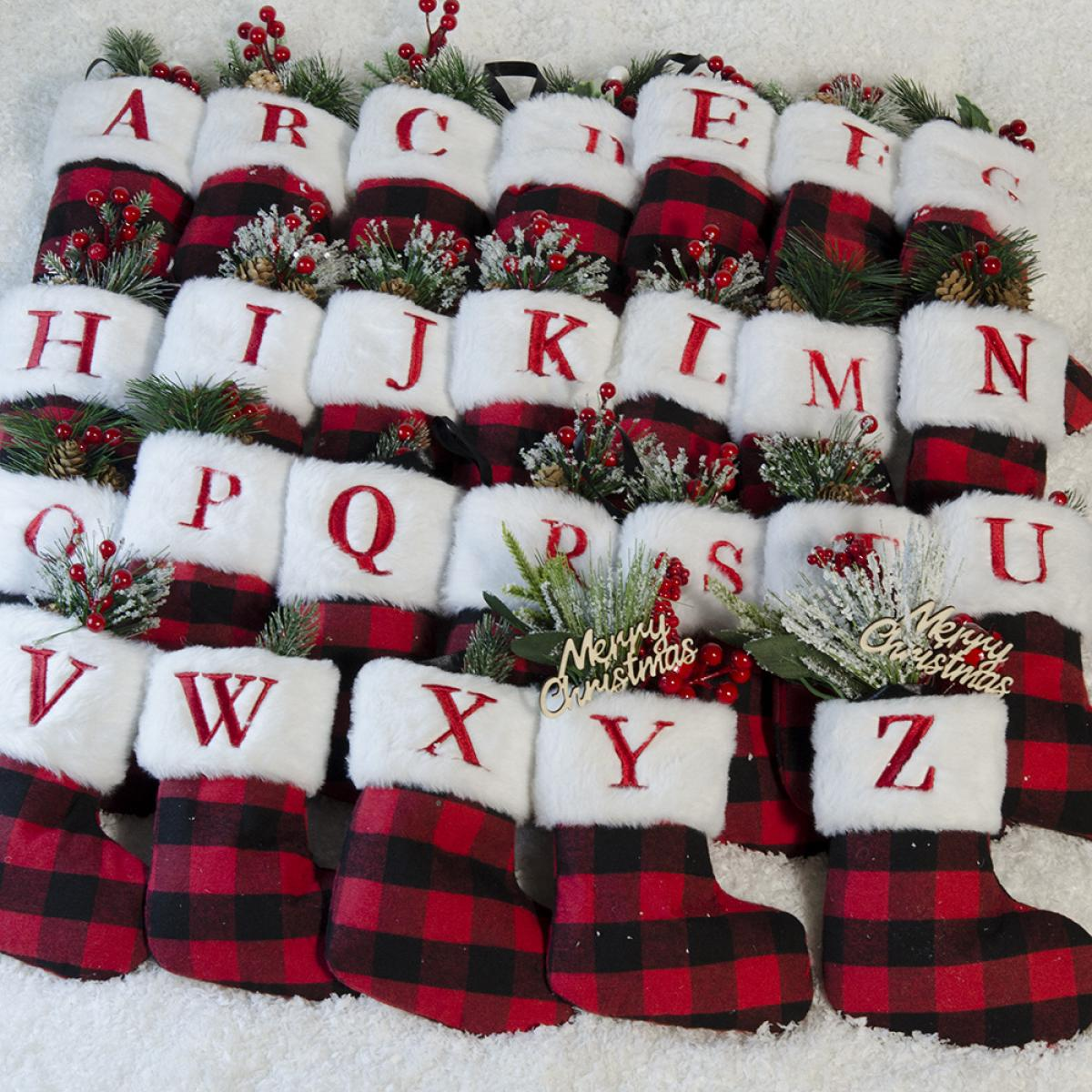 Weihnachtsstrümpfe in Reihen angeordnet, jeder mit einem Buchstaben von A bis Z. Sie sind rot und schwarz kariert mit weißem Pelzbesatz.