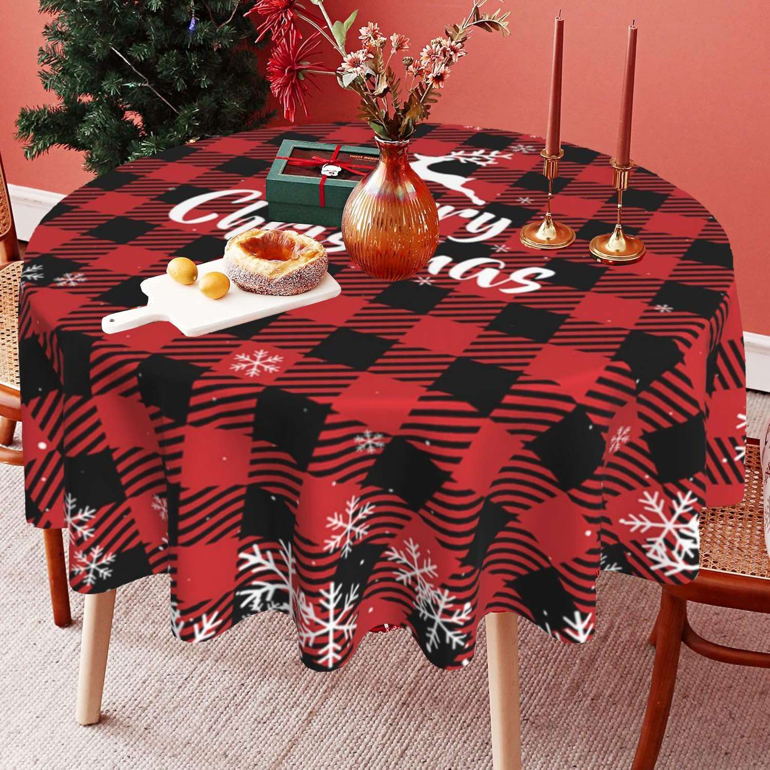 Weihnachtstisch mit rot-schwarzem Karomuster. Kuchen, Kerzen und Dekorationen auf dem Tisch. Weihnachtsbaum im Hintergrund.