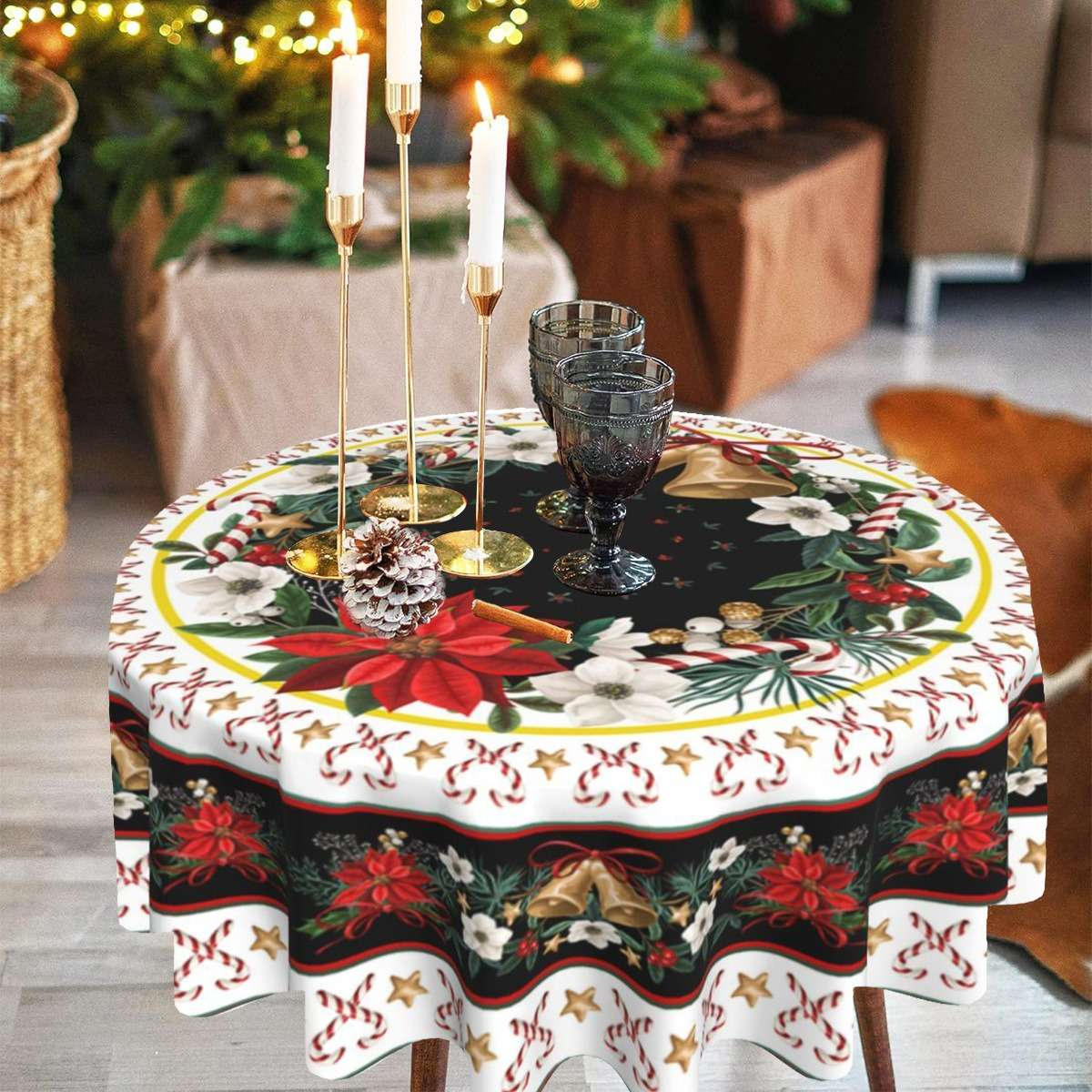 Ein runder Tisch mit einer weihnachtlichen Tischdecke. Kerzen, Gläser und Ornamente stehen auf dem Tisch. Weihnachtsbaum und Geschenke im Hintergrund.