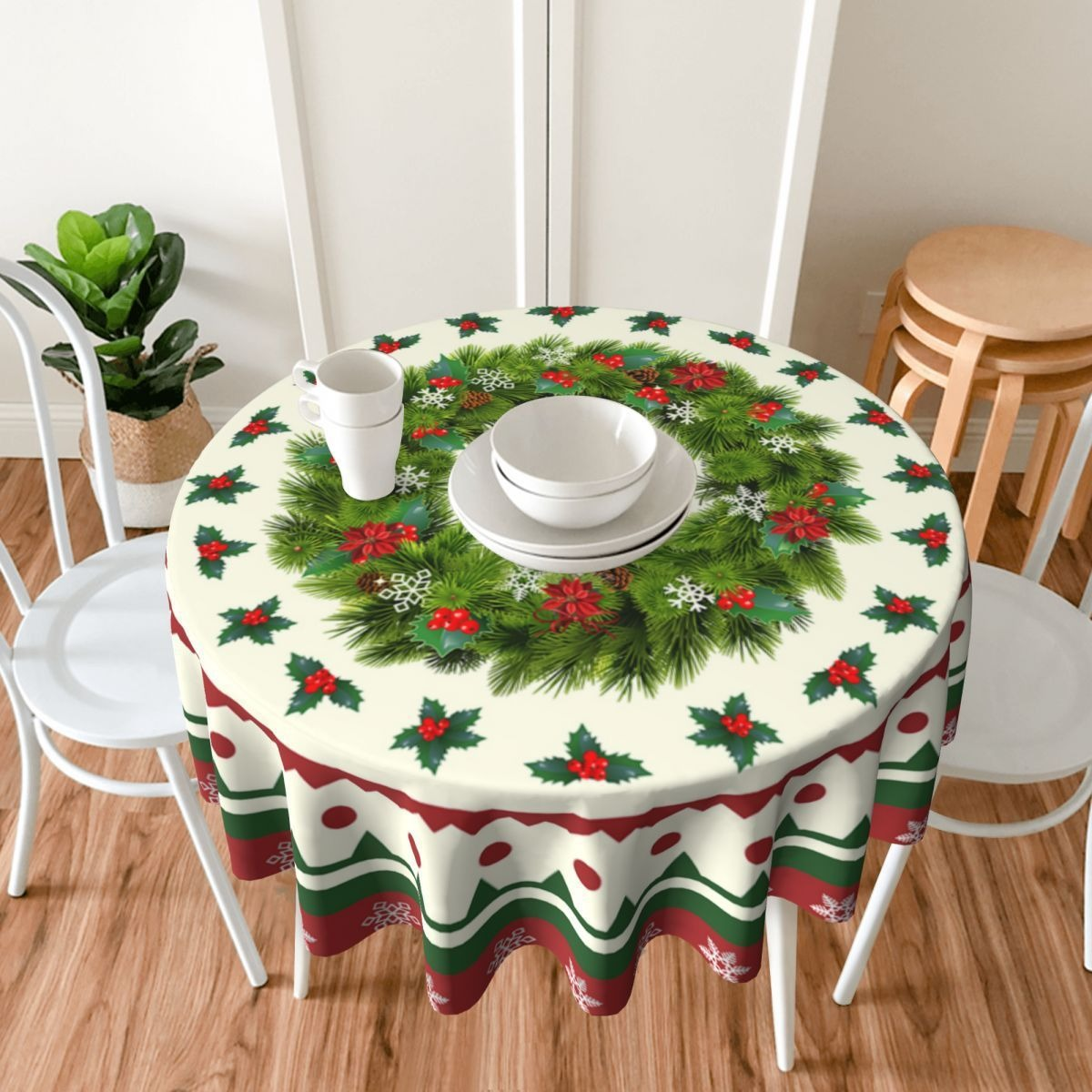 Runder Tisch mit Weihnachts-Tischdecke, zwei weiße Stühle und eine Zimmerpflanze.